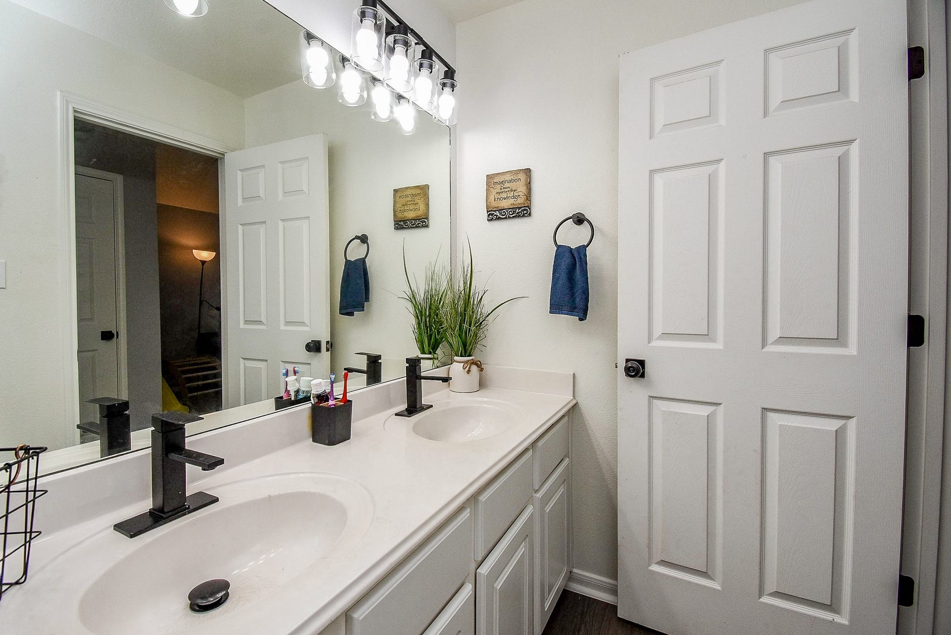 6703 Morning Glory Trace, Richmond, TX 77407 This photo showcases a modern bathroom featuring a double vanity with sleek black fixtures, ample counter space, and a large mirror. The room is well-lit with stylish lighting and has a clean, minimalist design.