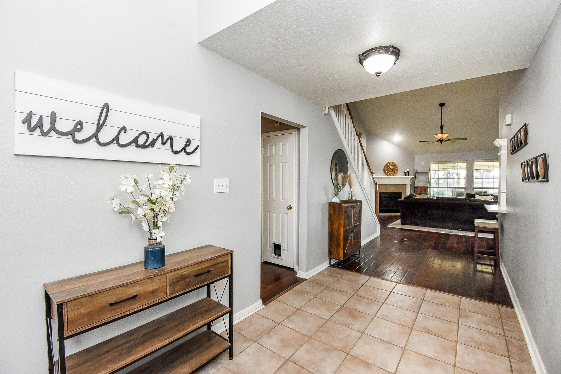 6703 Morning Glory Trace, Richmond, TX 77407 Bright entryway with tile flooring and a welcoming sign. Leads into a spacious living area with hardwood floors, a cozy fireplace, and large windows for natural light. Stairs to the upper level are visible, creating an open and inviting atmosphere.