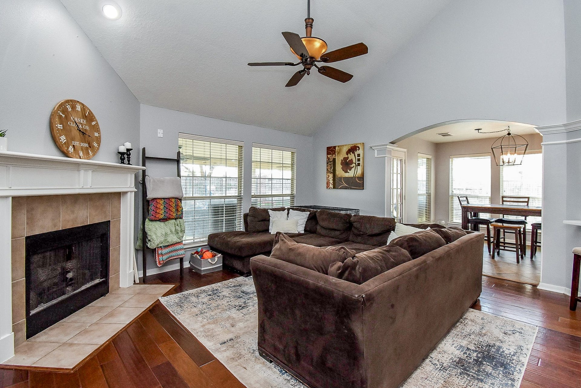 6703 Morning Glory Trace, Richmond, TX 77407 This inviting living room features a vaulted ceiling and a cozy fireplace. It has large windows for natural light, and an open archway leading to the dining area. Perfect for comfortable living and entertaining.