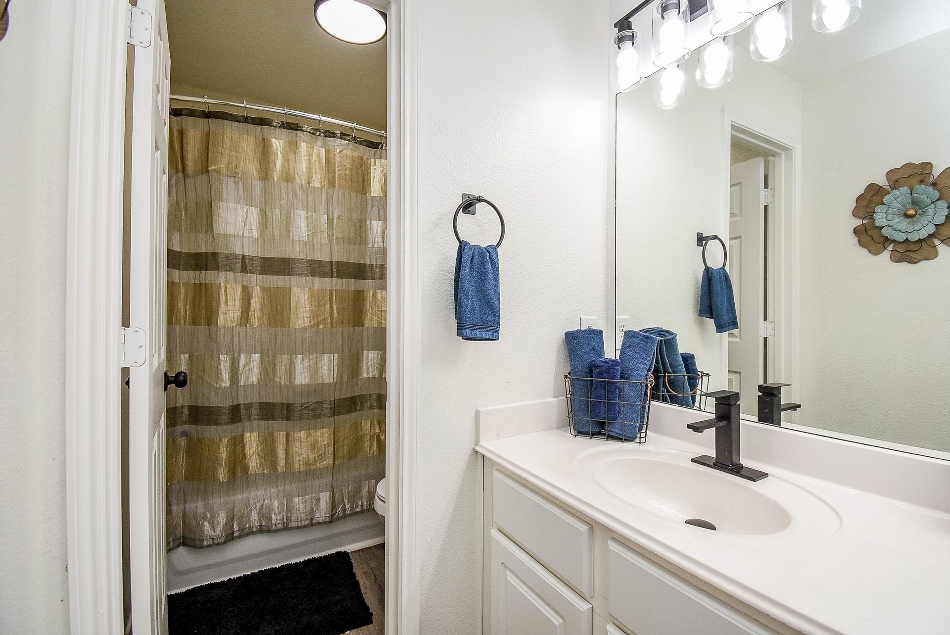 6703 Morning Glory Trace, Richmond, TX 77407 This bathroom features a clean, modern design with a white vanity, black fixtures, and a large mirror. There's ample lighting above the sink.