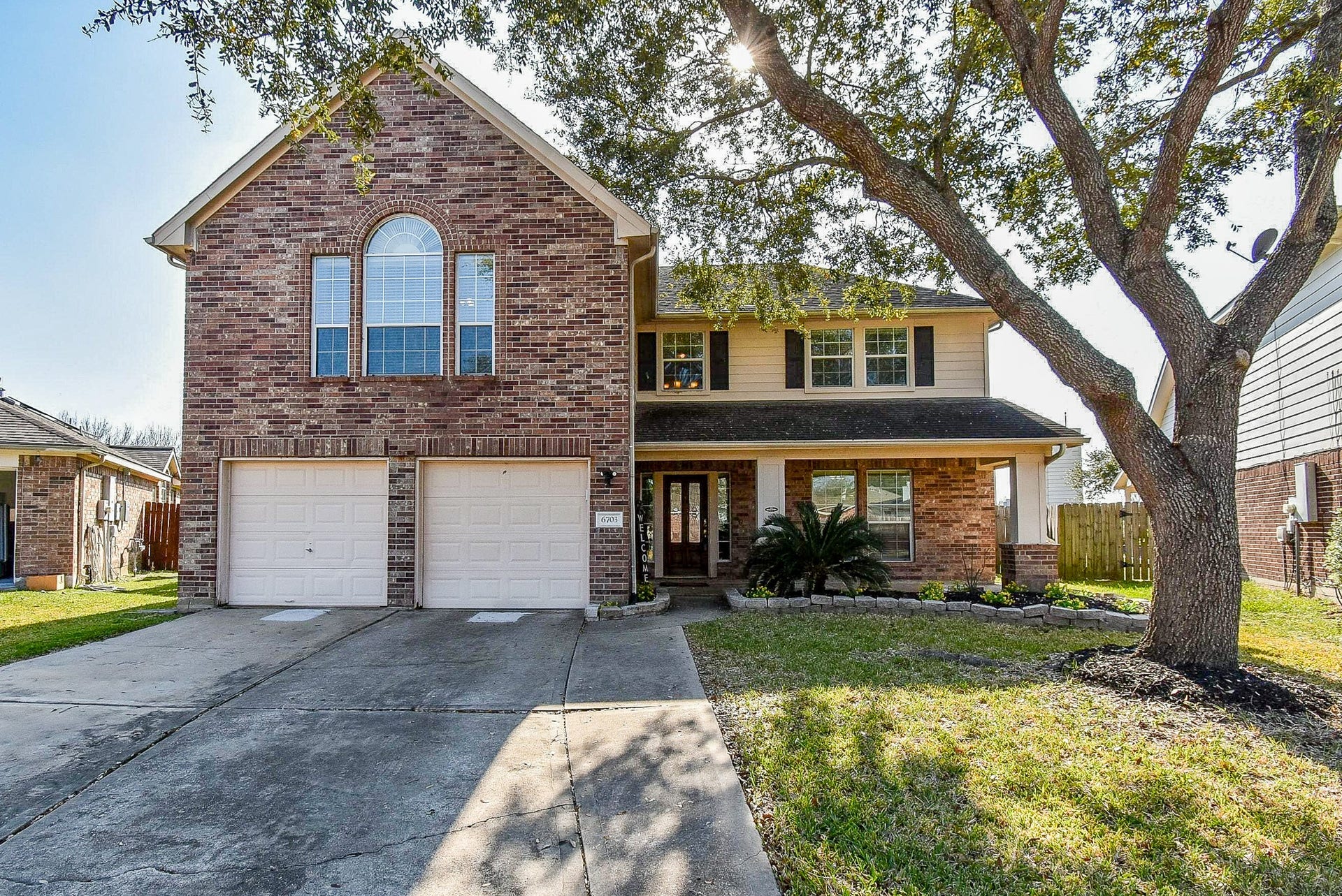 6703 Morning Glory Trace, Richmond, TX 77407 This charming two-story brick home features a welcoming front porch, a spacious two-car garage, and a well-maintained front yard with mature trees.
