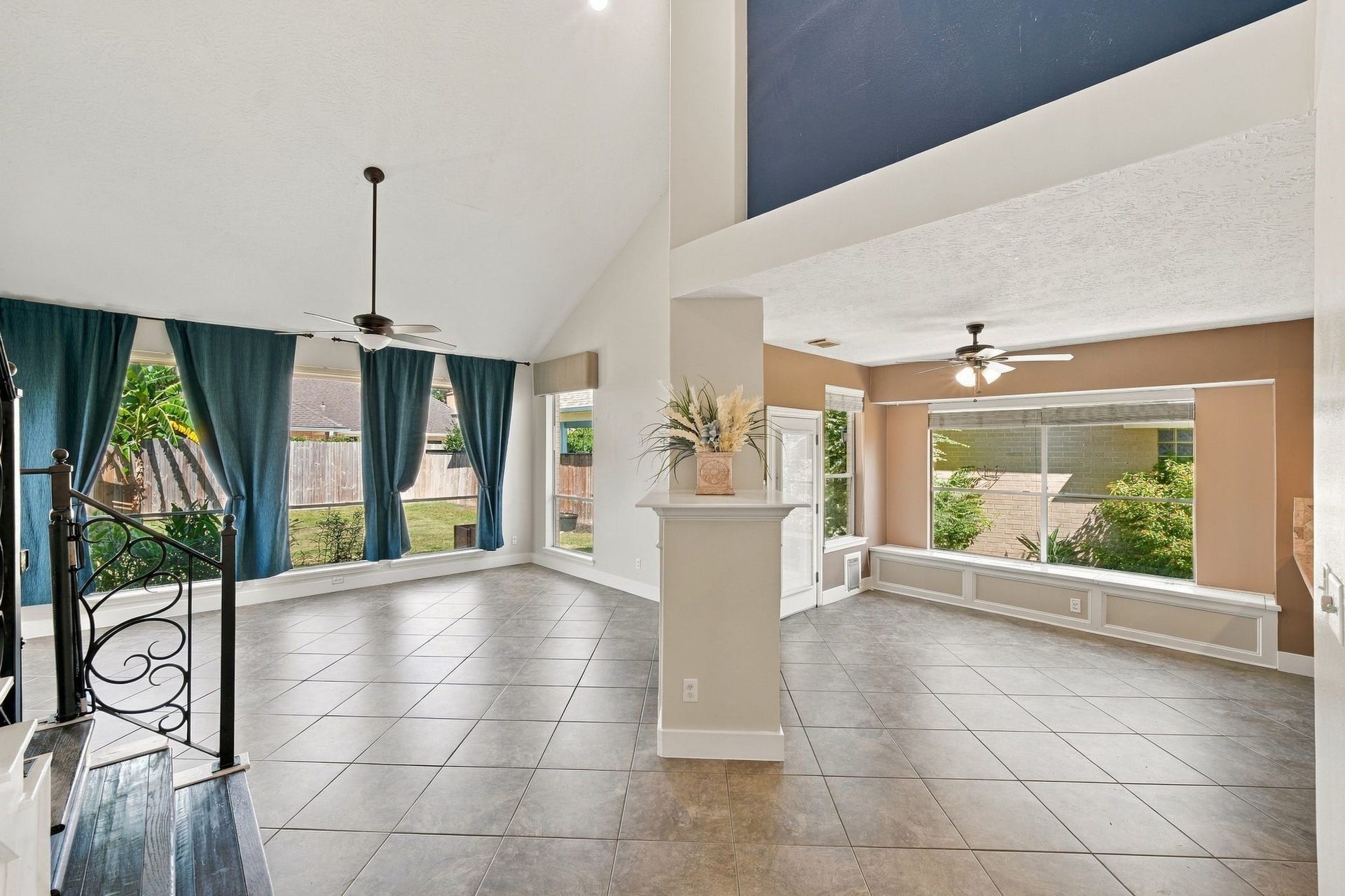 201 Lago Vista Street, League City, TX 77565 Spacious and filled with natural light, this versatile, unstaged living area features high ceilings, elegant tile flooring, and large windows overlooking lush greenery, offering a perfect canvas for your personal touch.