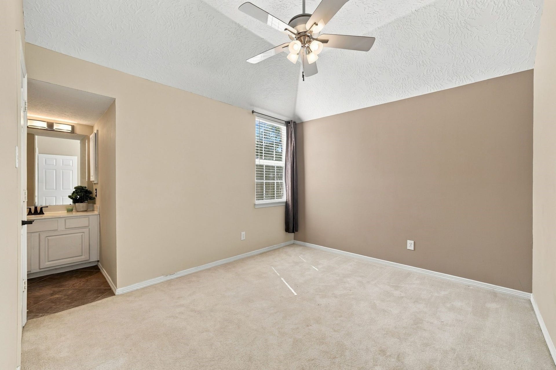 201 Lago Vista Street, League City, TX 77565 Discover the potential of this unstaged room featuring a vaulted ceiling, soft carpet, and ample natural light, leading to a cozy en-suite bathroom.