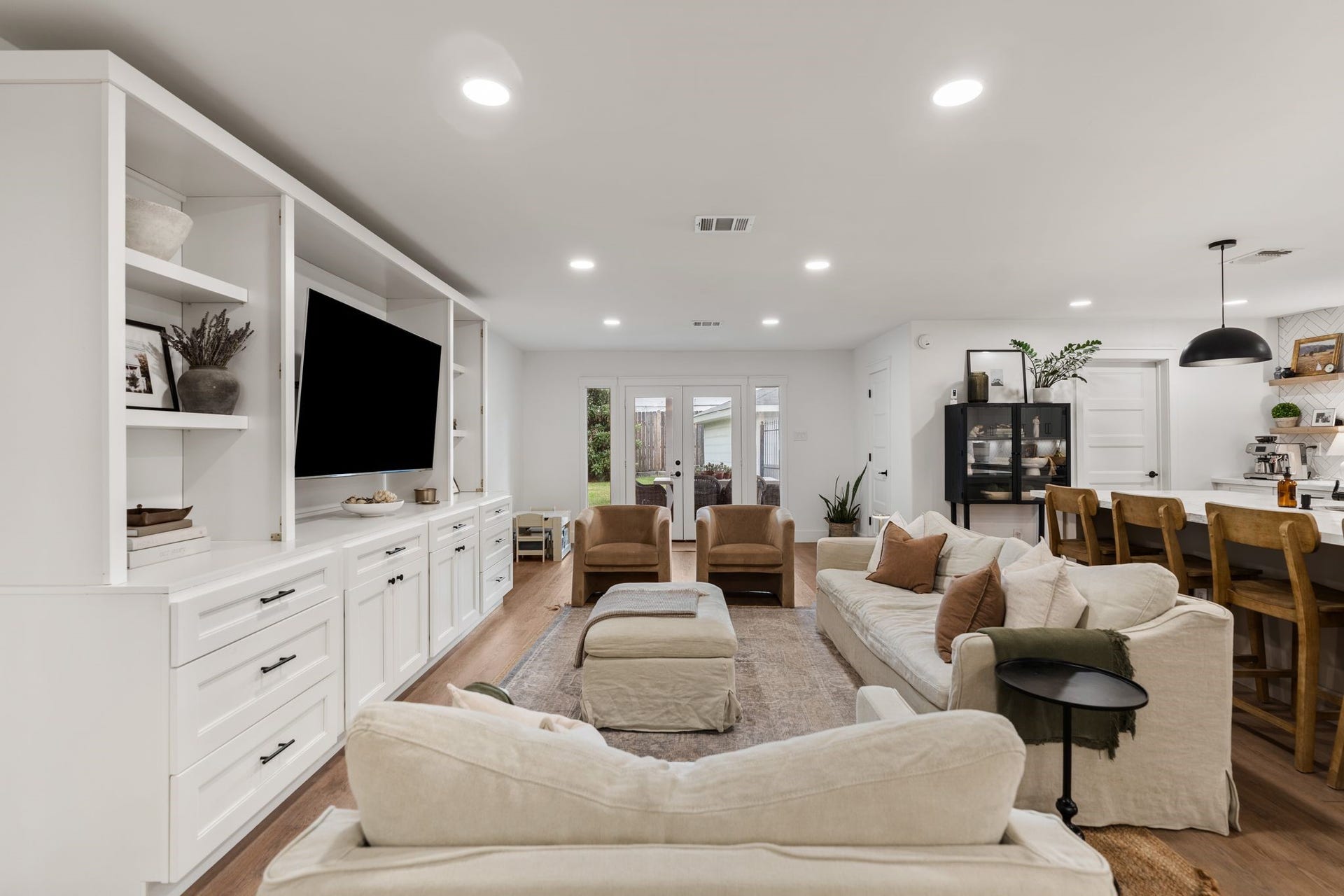 9206 Kapri Lane, Houston, TX 77025 Generously sized living area featuring custom floor-to-ceiling built-ins, updated flooring and French doors opening directly to the backyard and covered patio.
