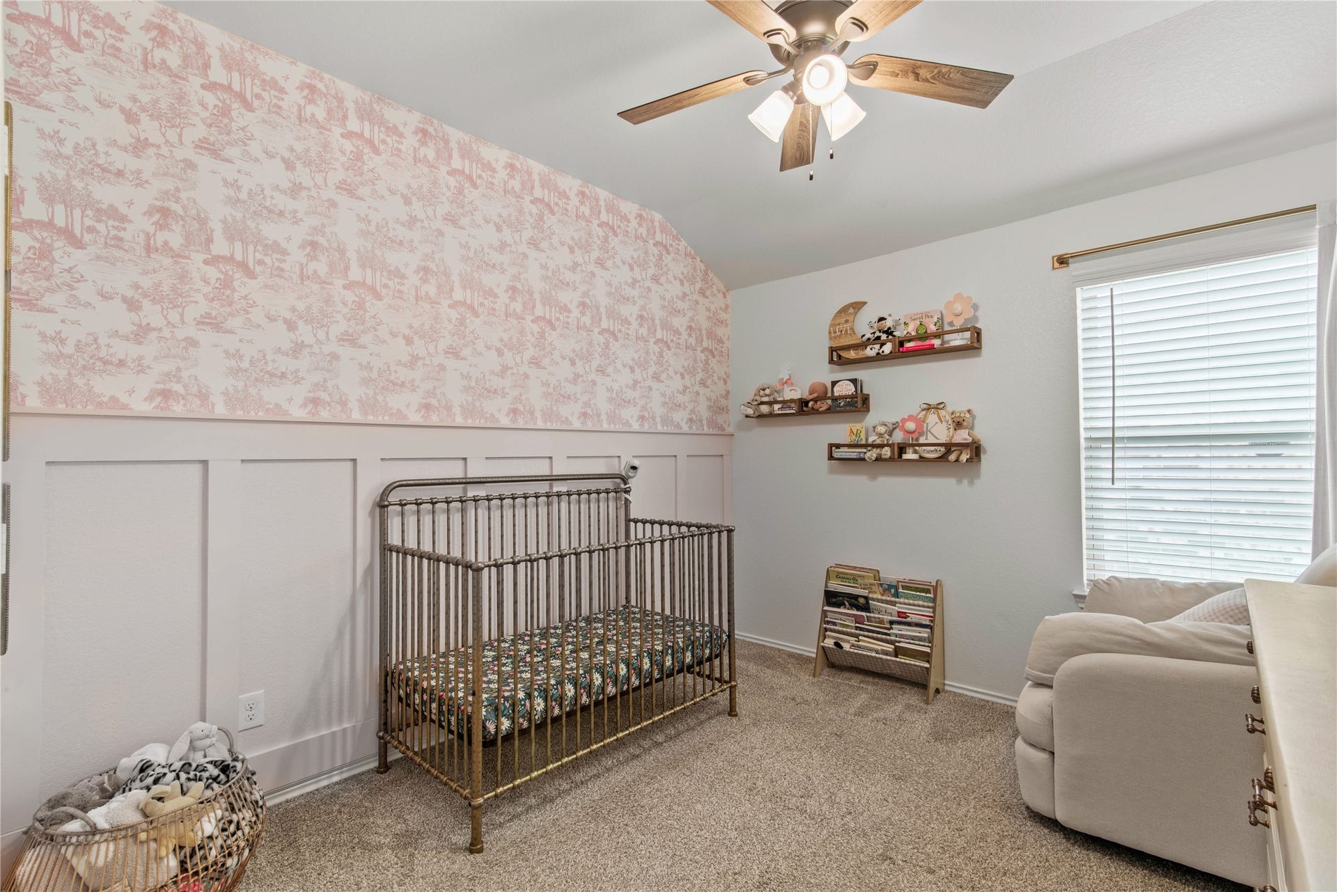 Charming nursery featuring soft pink wallpaper and a cozy atmosphere, complete with a classic crib and plush seating area.