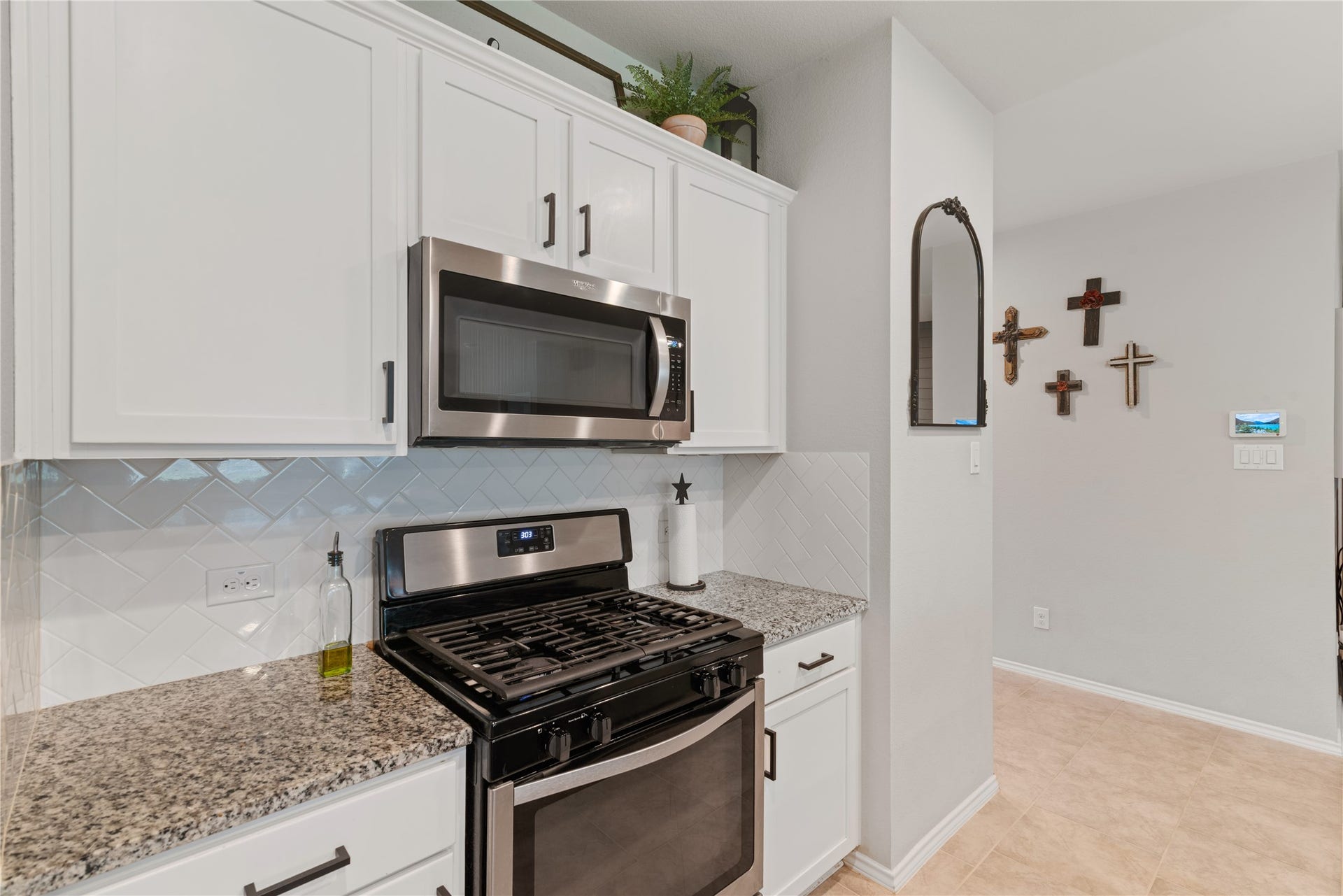Modern kitchen featuring sleek stainless steel appliances, granite countertops, and crisp white cabinetry, complemented by a stylish herringbone tile backsplash.