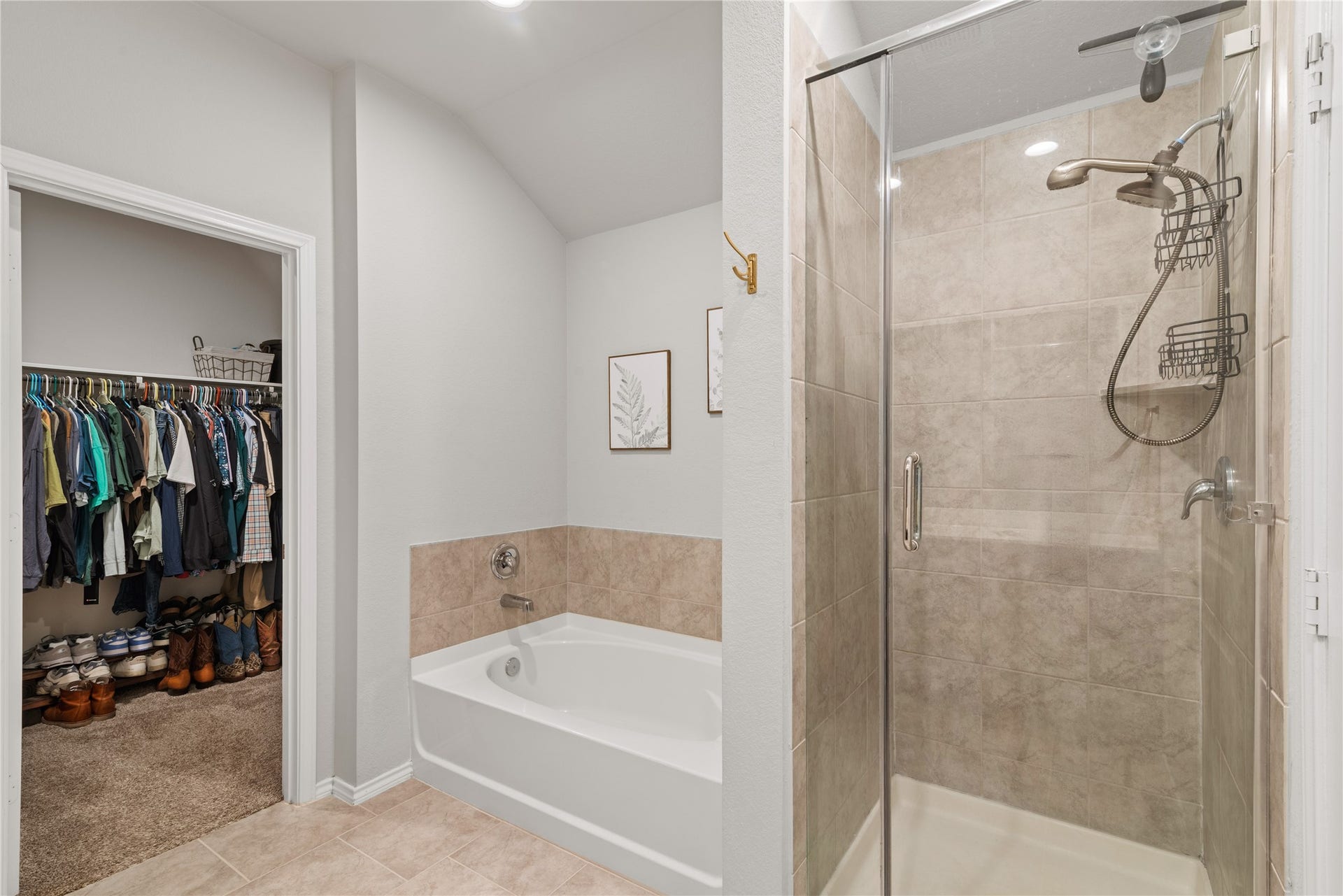 Spacious bathroom featuring a sleek glass-enclosed shower, a relaxing bathtub, and convenient access to a walk-in closet.
