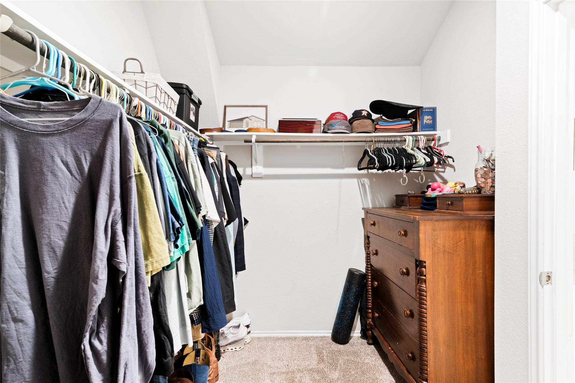 Spacious walk-in closet with ample hanging space, shelving for accessories, and a classic wooden dresser, offering organized storage solutions.