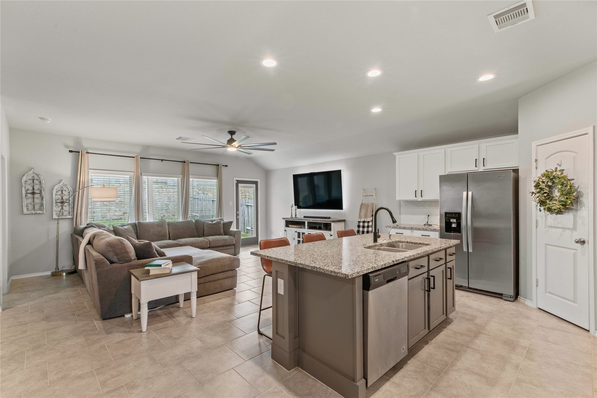 Spacious open-concept living area with a modern kitchen featuring granite countertops, stainless steel appliances, and a cozy living room with abundant natural light.
