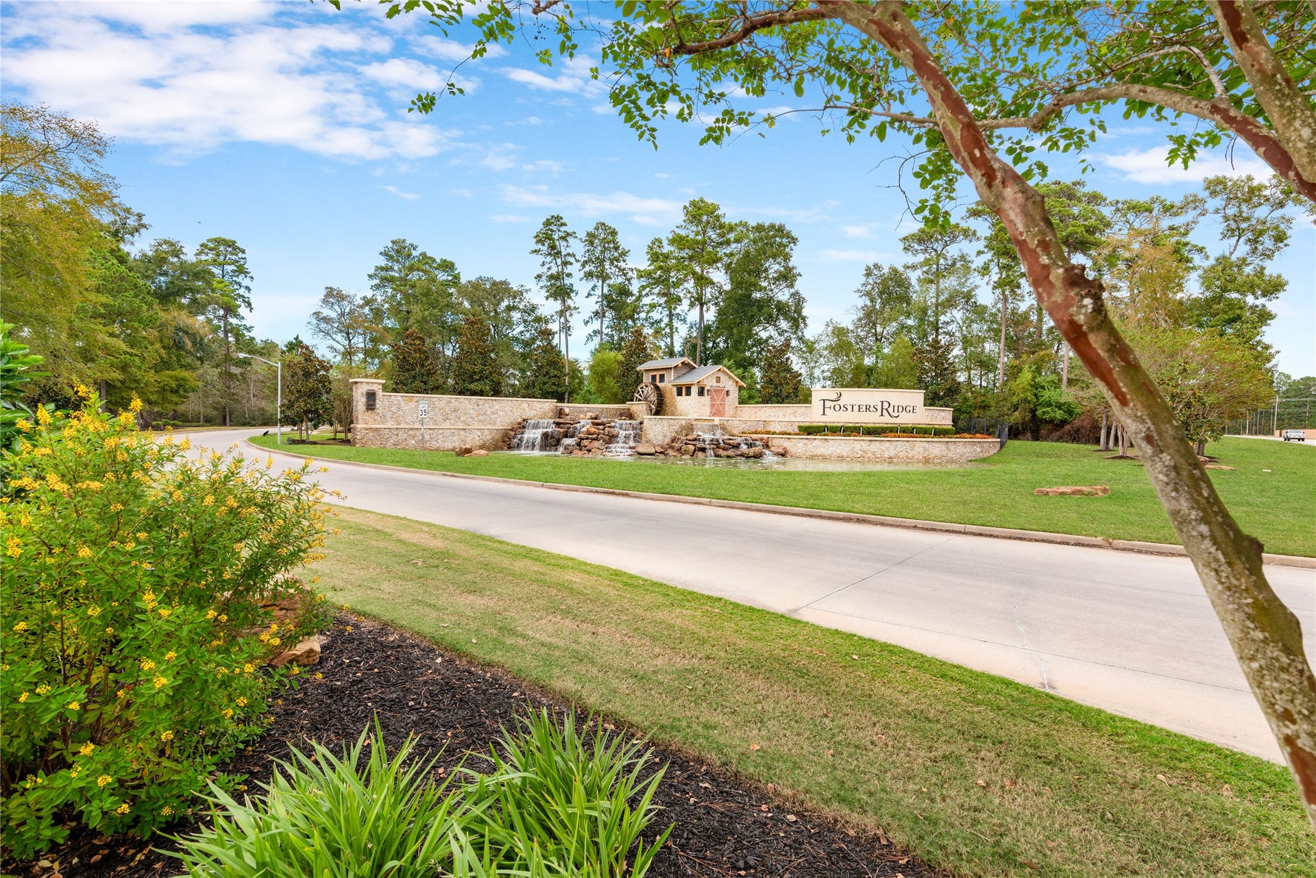 Discover the charm of Fosters Ridge, an inviting community surrounded by lush greenery and scenic landscapes, featuring a welcoming stone entrance and tranquil waterfall.