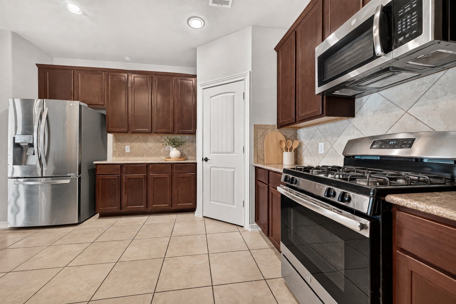 3658 Diamond Creek Drive, Missouri City, TX 77459 Kitchen equipped with stainless steel appliances, gas cooking, and ample storage. Neutral tile backsplash and flooring complete the space.