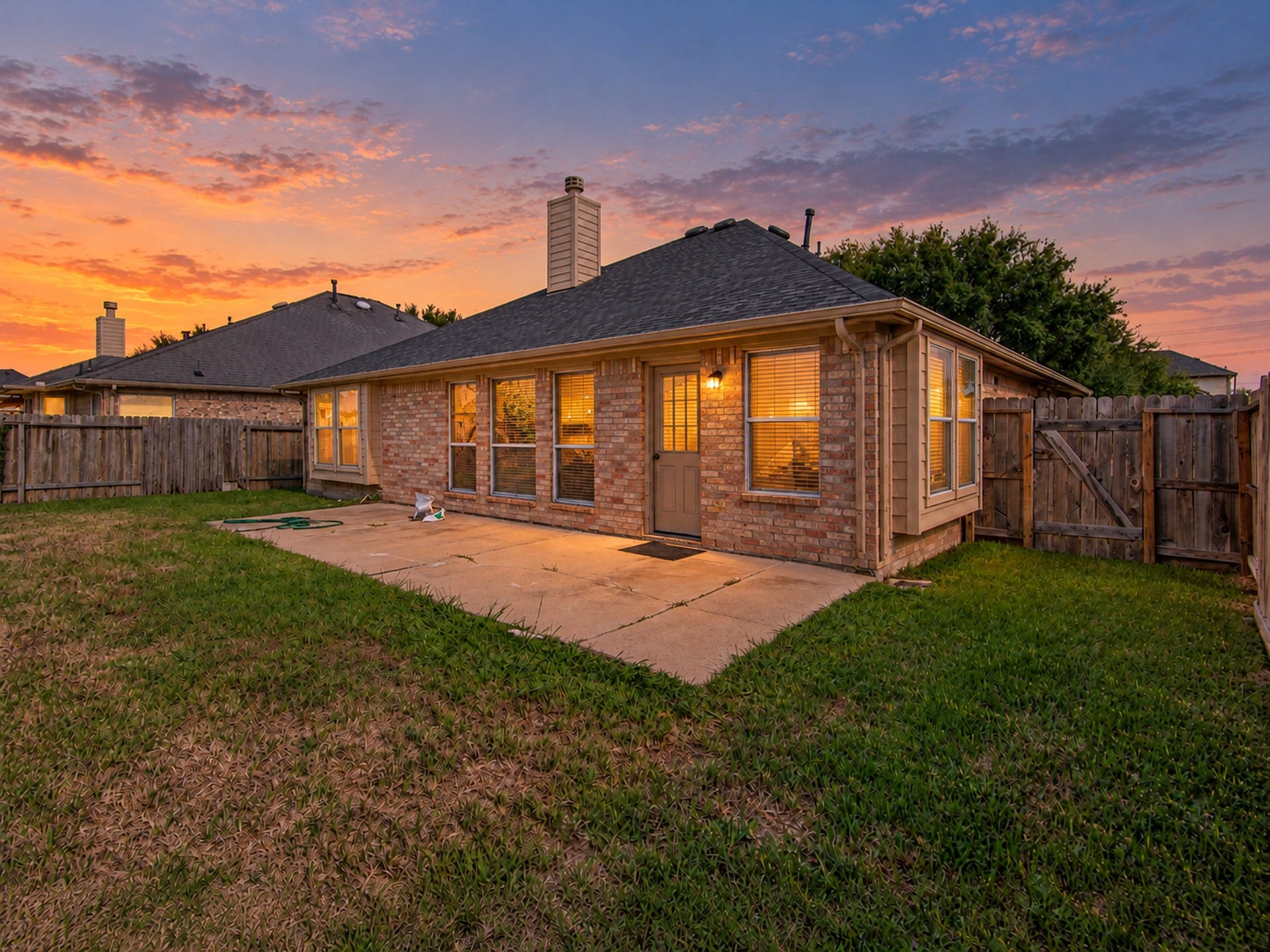 12906 Brook Arbor Court, Pearland, TX 77584 Rear exterior view showcasing the brick facade, patio, and fenced backyard