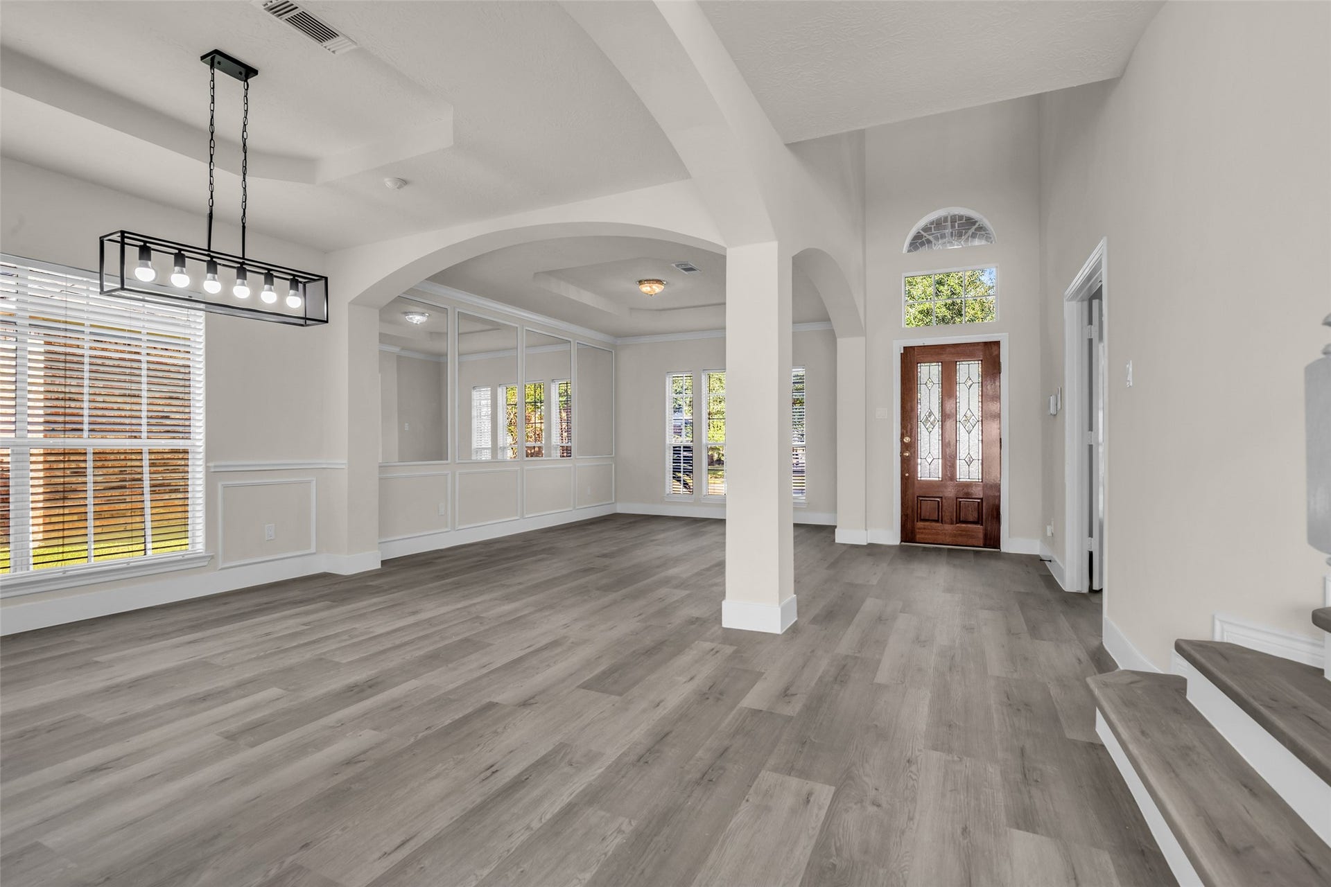 6110 Four River Drive, Richmond, TX 77469 Elegant entryway with high ceilings, modern light fixtures, and abundant natural light, featuring stylish wood flooring and classic architectural detailing.