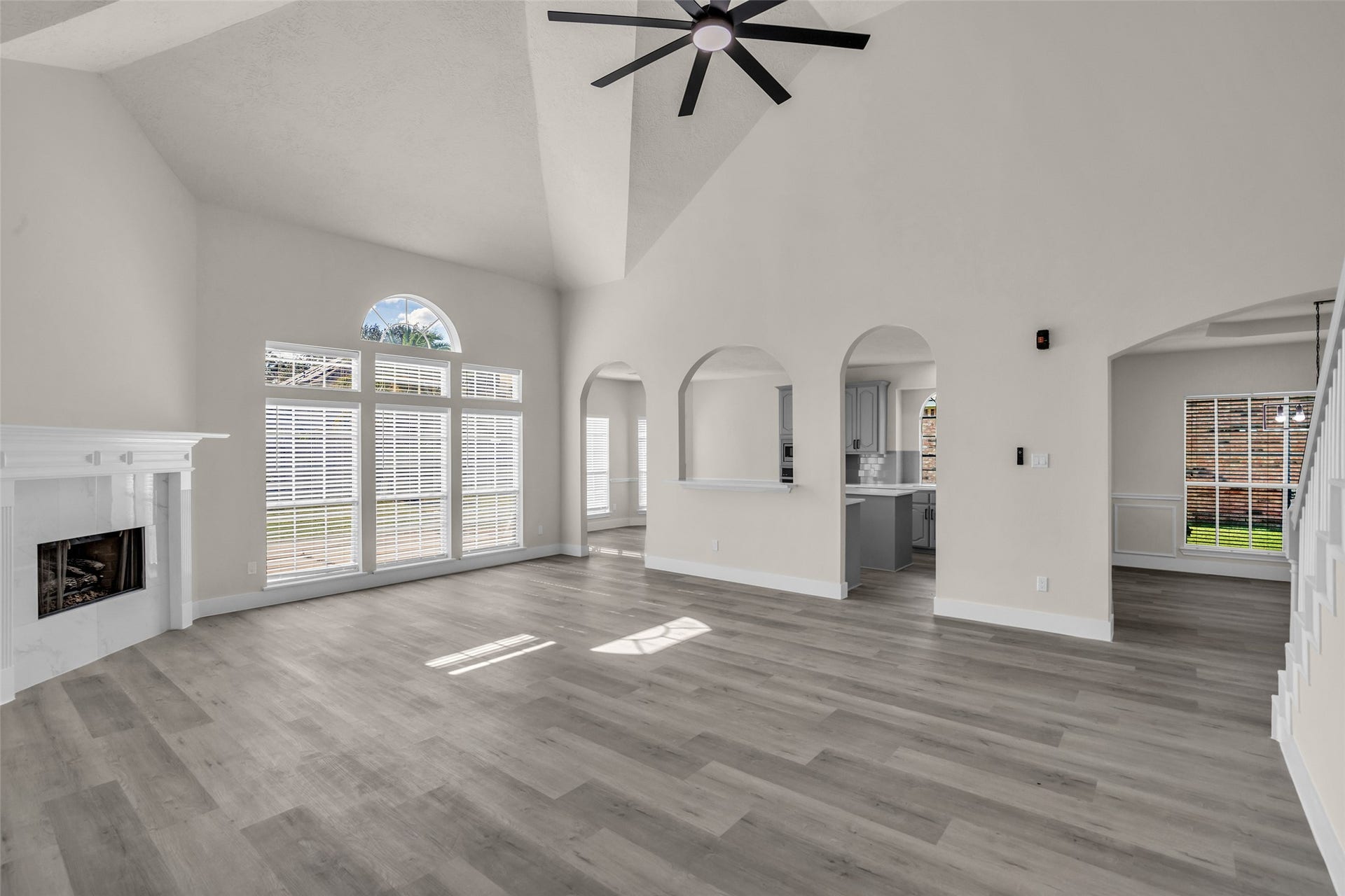 6110 Four River Drive, Richmond, TX 77469 Spacious living area with high vaulted ceilings, abundant natural light from large windows, and elegant archways leading to a modern kitchen.