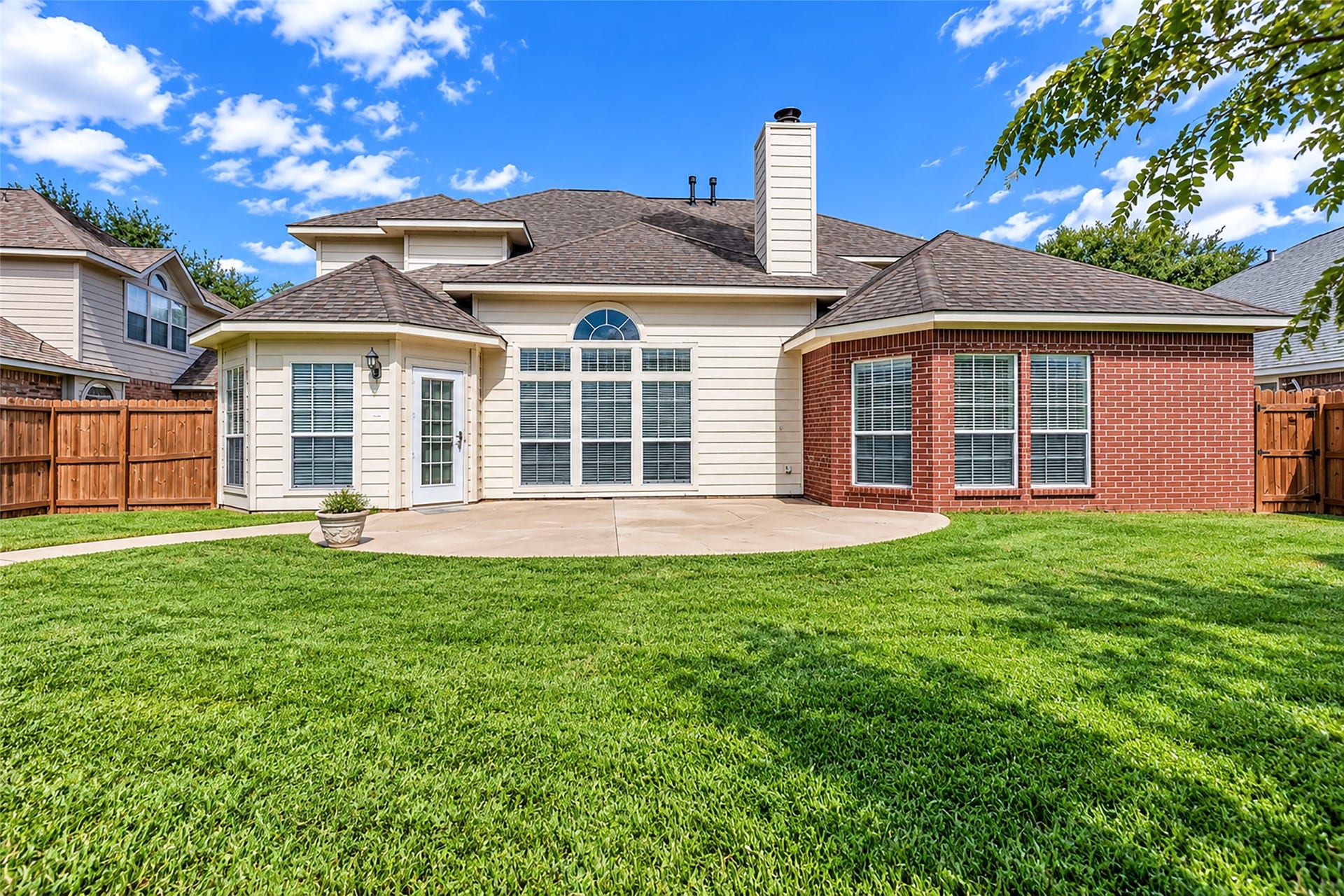 6110 Four River Drive, Richmond, TX 77469 Charming backyard with a spacious patio, lush green lawn, and a blend of brick and siding exterior, offering privacy and a perfect setting for outdoor gatherings.