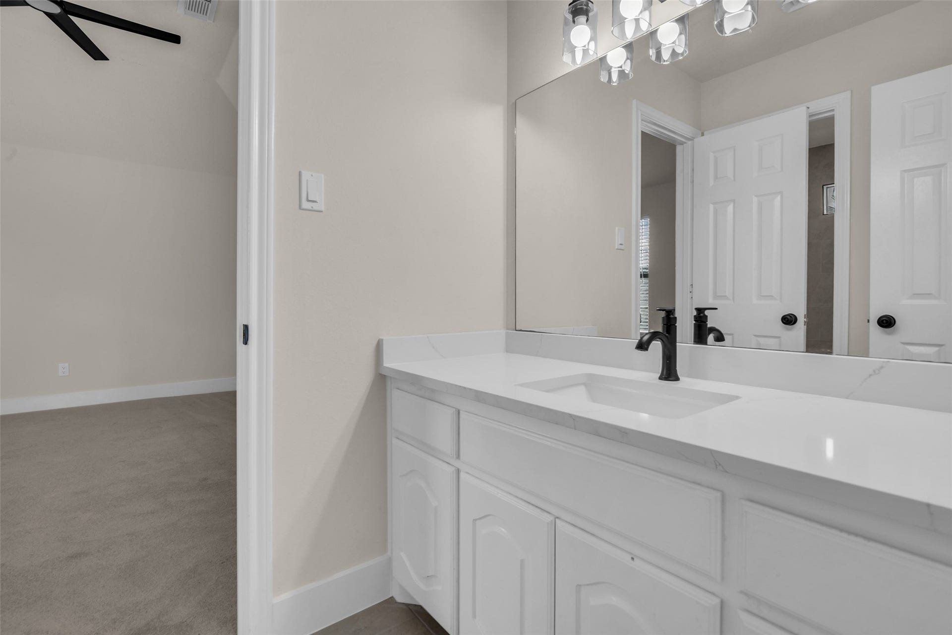 6110 Four River Drive, Richmond, TX 77469 Secondary bathroom with sleek white cabinetry, a spacious countertop, and a large mirror, offering a clean and elegant look.