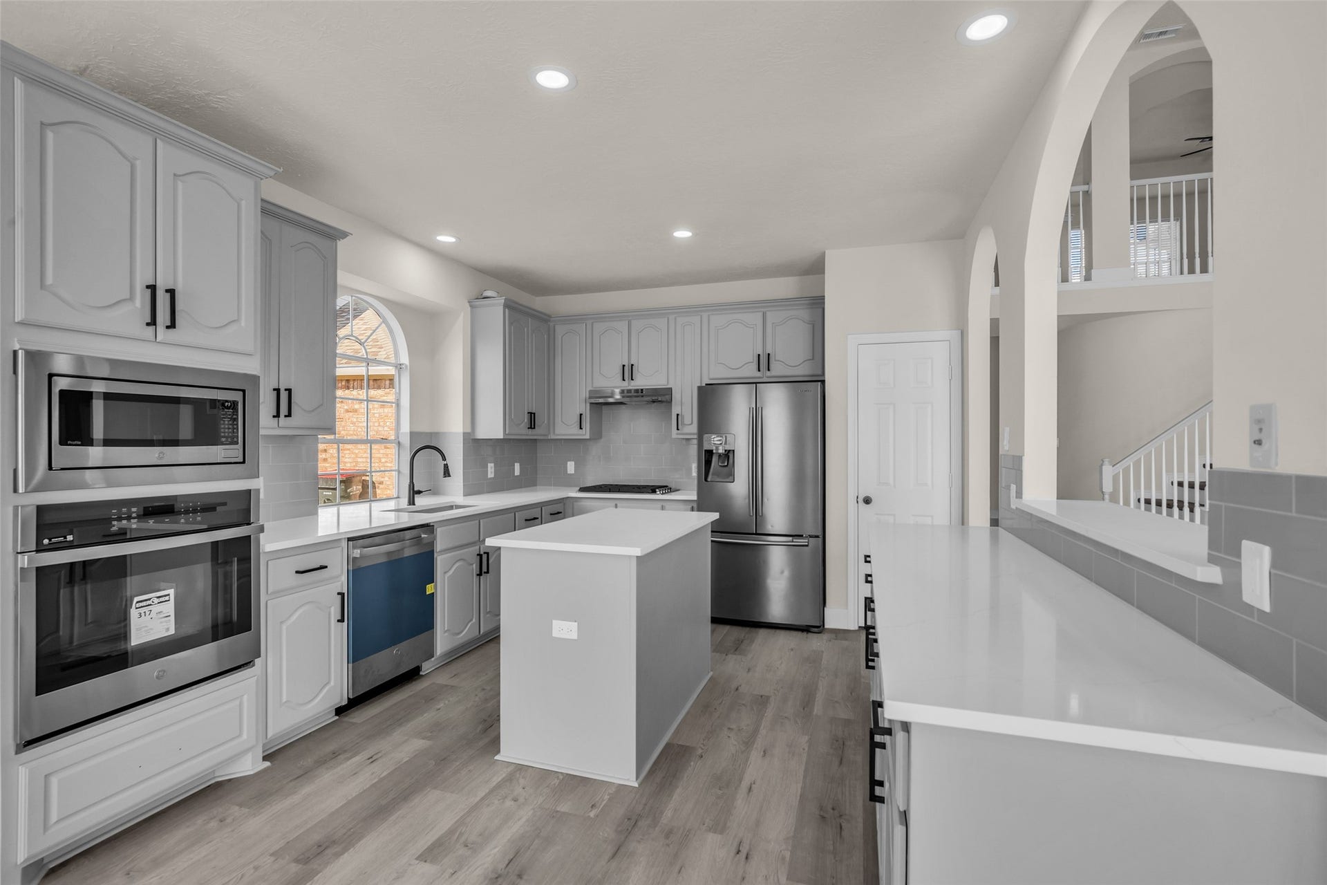 6110 Four River Drive, Richmond, TX 77469 A modern kitchen with sleek stainless steel appliances, elegant gray cabinetry, and a central island, perfect for culinary enthusiasts. The space is enhanced by a kitchen window for all that natural light!