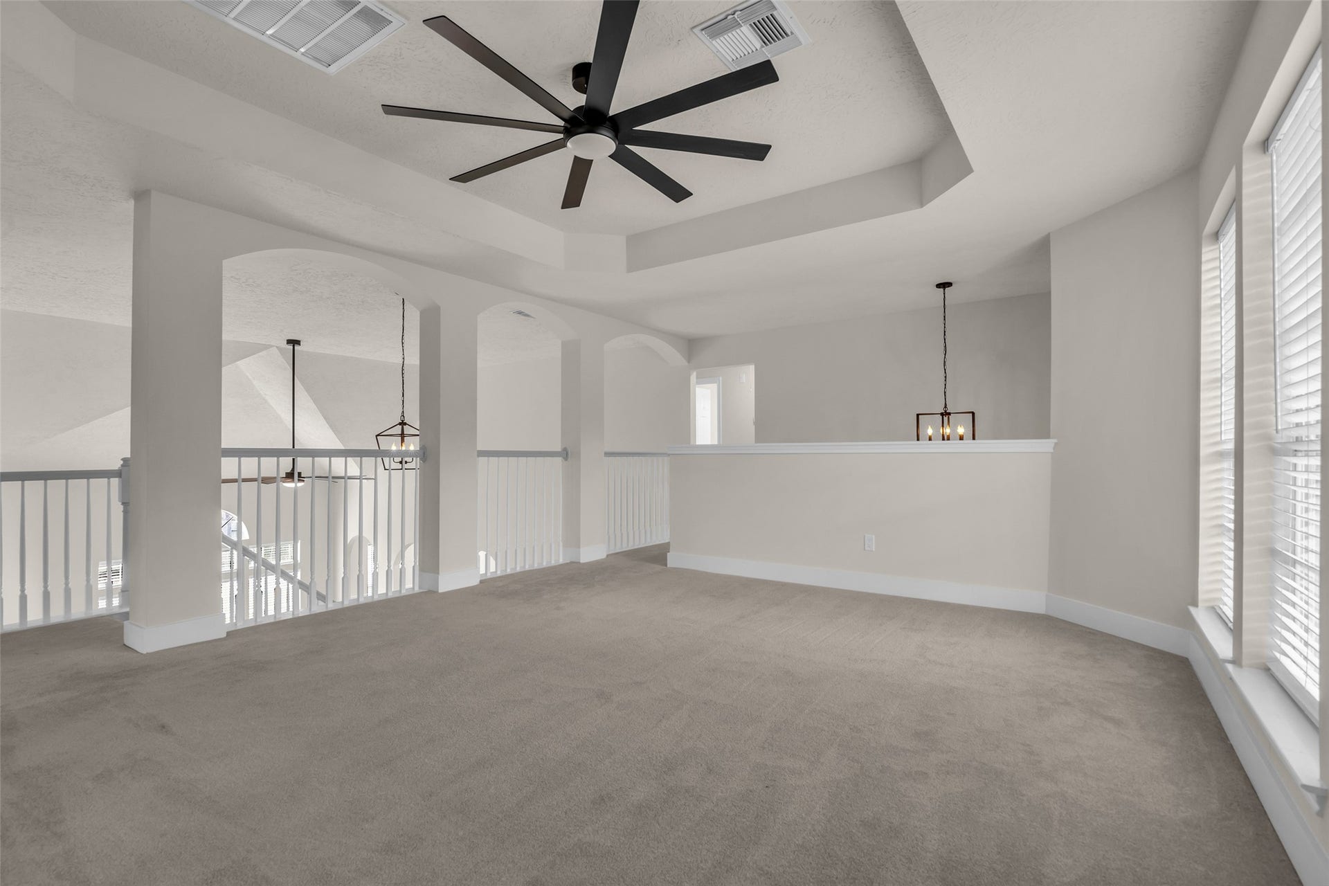 6110 Four River Drive, Richmond, TX 77469 Open game room with abundant natural light, modern ceiling fan, and elegant railing overlooking the floor below, perfect for a versatile living area