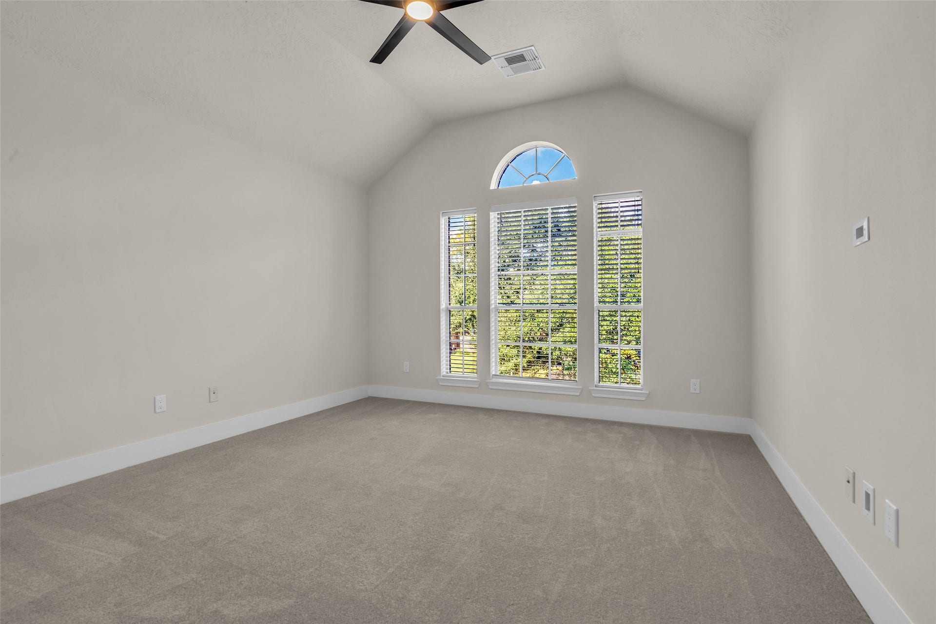 6110 Four River Drive, Richmond, TX 77469 Third bedroom with vaulted ceilings, large arched window providing abundant natural light, and neutral carpeting, perfect for creating a cozy retreat.