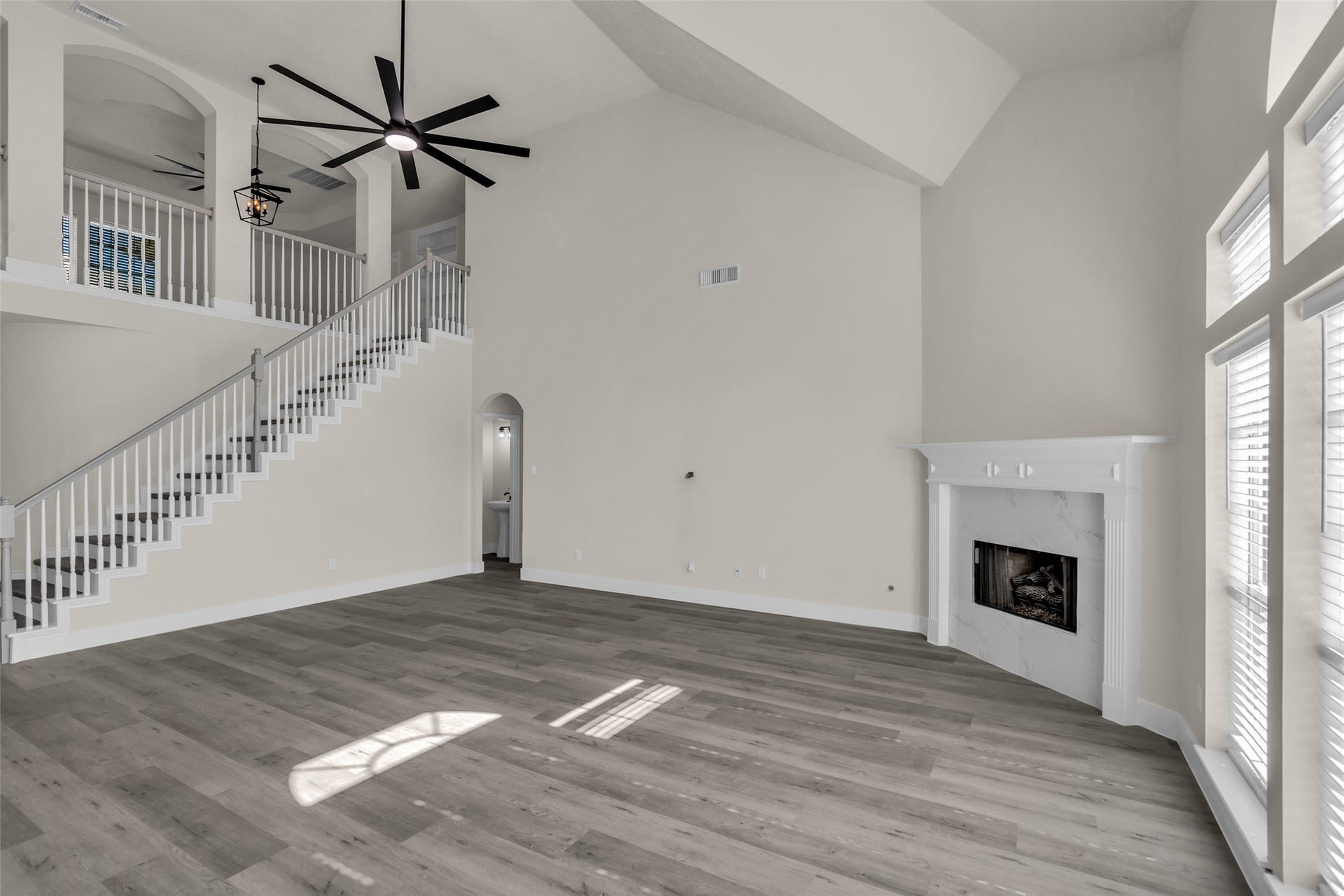 6110 Four River Drive, Richmond, TX 77469 Spacious living room featuring high ceilings, elegant staircase, and a cozy fireplace, enhanced by abundant natural light from large windows.