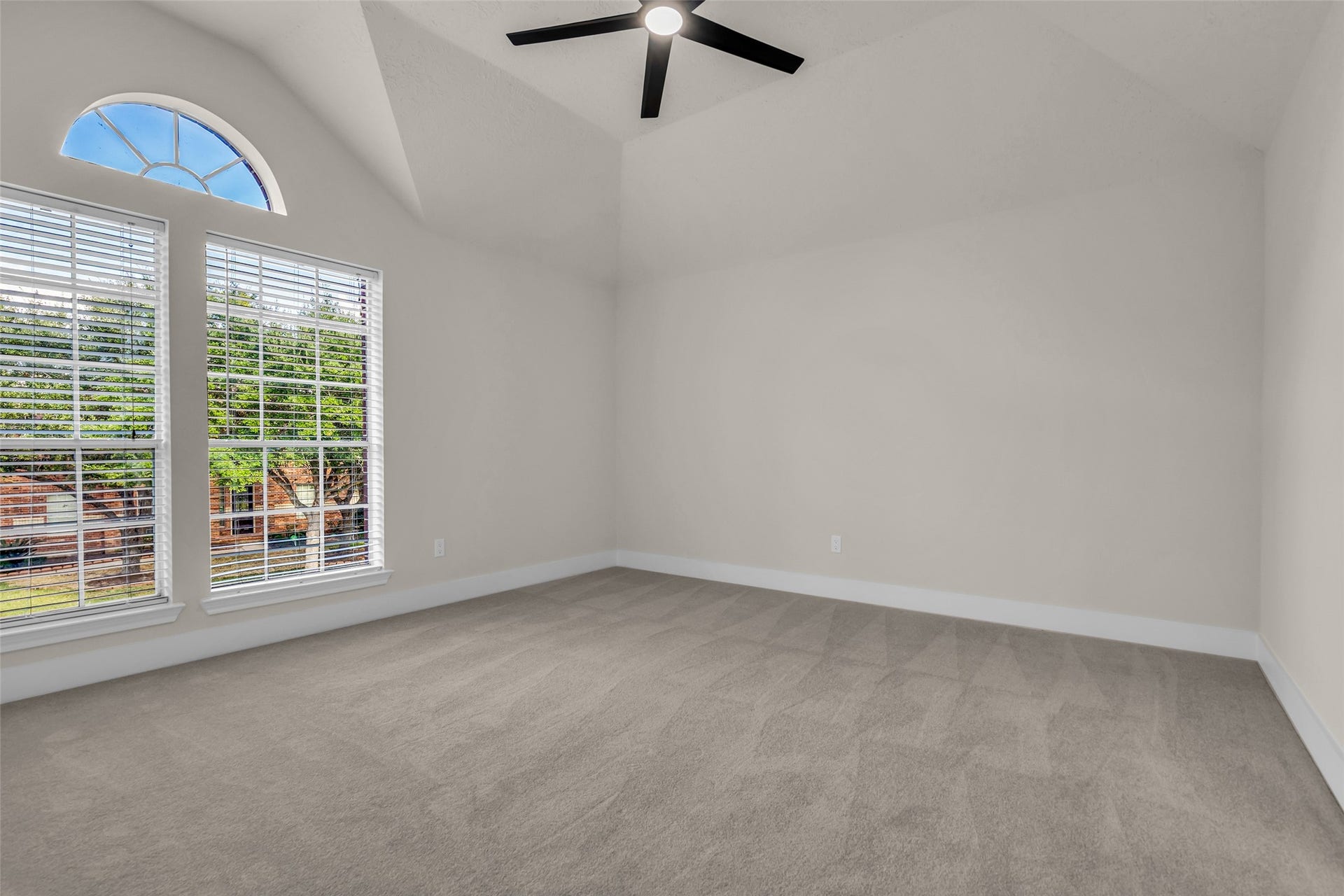 6110 Four River Drive, Richmond, TX 77469 Spacious bedroom with vaulted ceilings, large arched window, and abundant natural light, complemented by neutral carpeting and a modern ceiling fan.