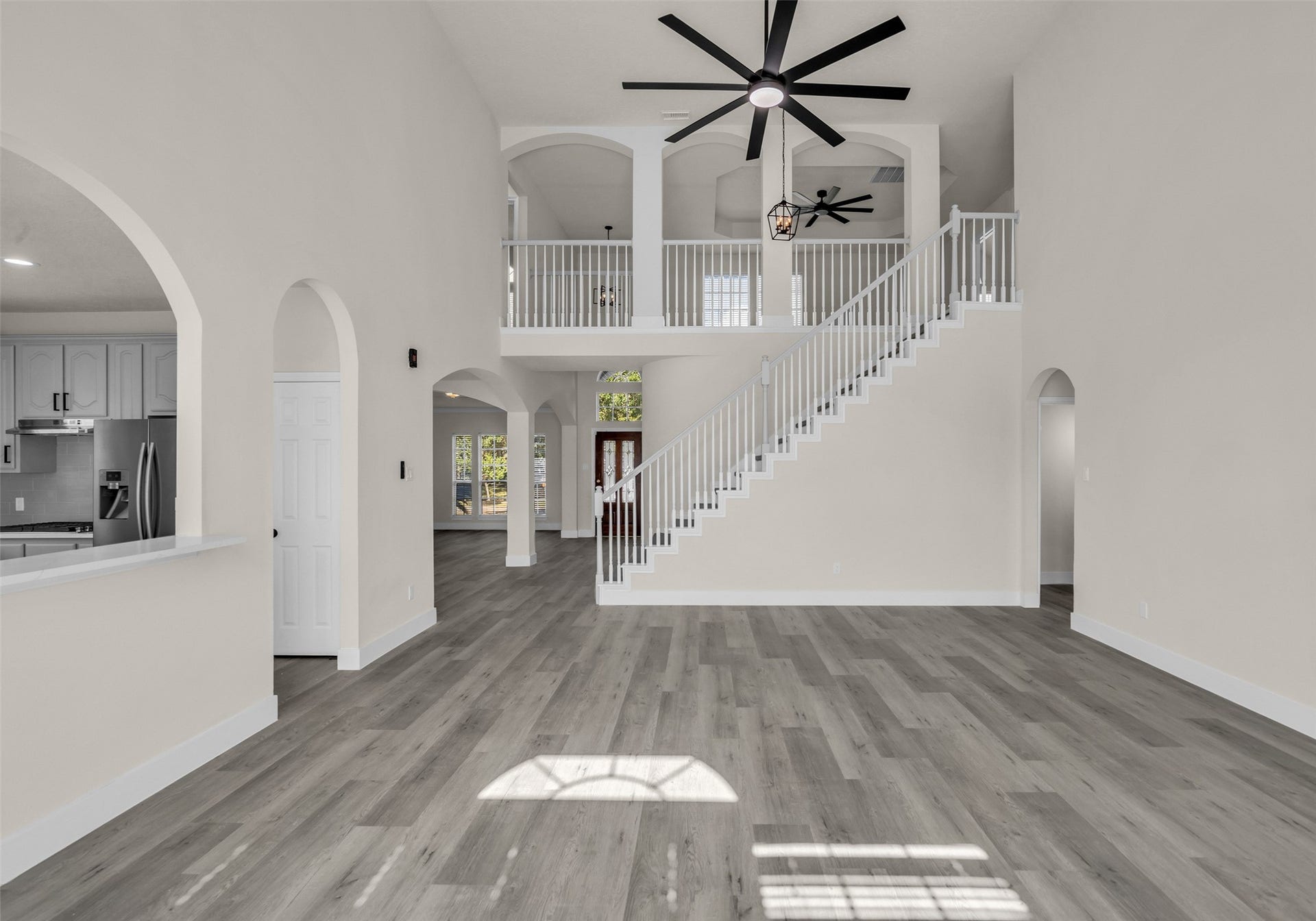 6110 Four River Drive, Richmond, TX 77469 Stunning open living space with high ceilings, elegant staircase, and abundant natural light. The modern kitchen features sleek appliances and a breakfast bar, seamlessly connecting to the living area.