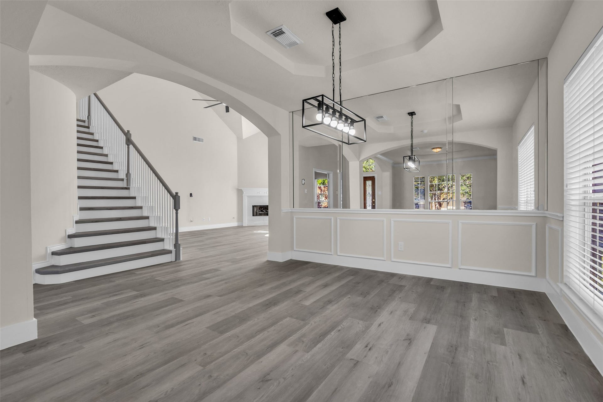 6110 Four River Drive, Richmond, TX 77469 Elegant open-concept living area with high ceilings, modern lighting, and a graceful staircase. The space features large windows and sleek wood flooring, creating a bright and inviting atmosphere.