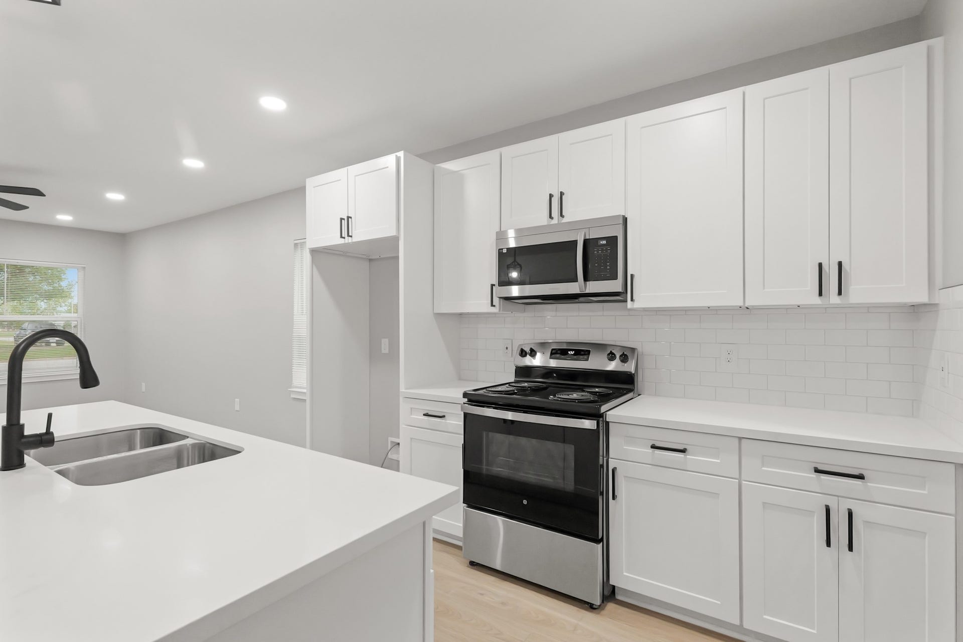 The crisp white cabinetry, enhanced with updated hardware, is perfectly complemented by recessed lighting, creating a bright and inviting ambiance.