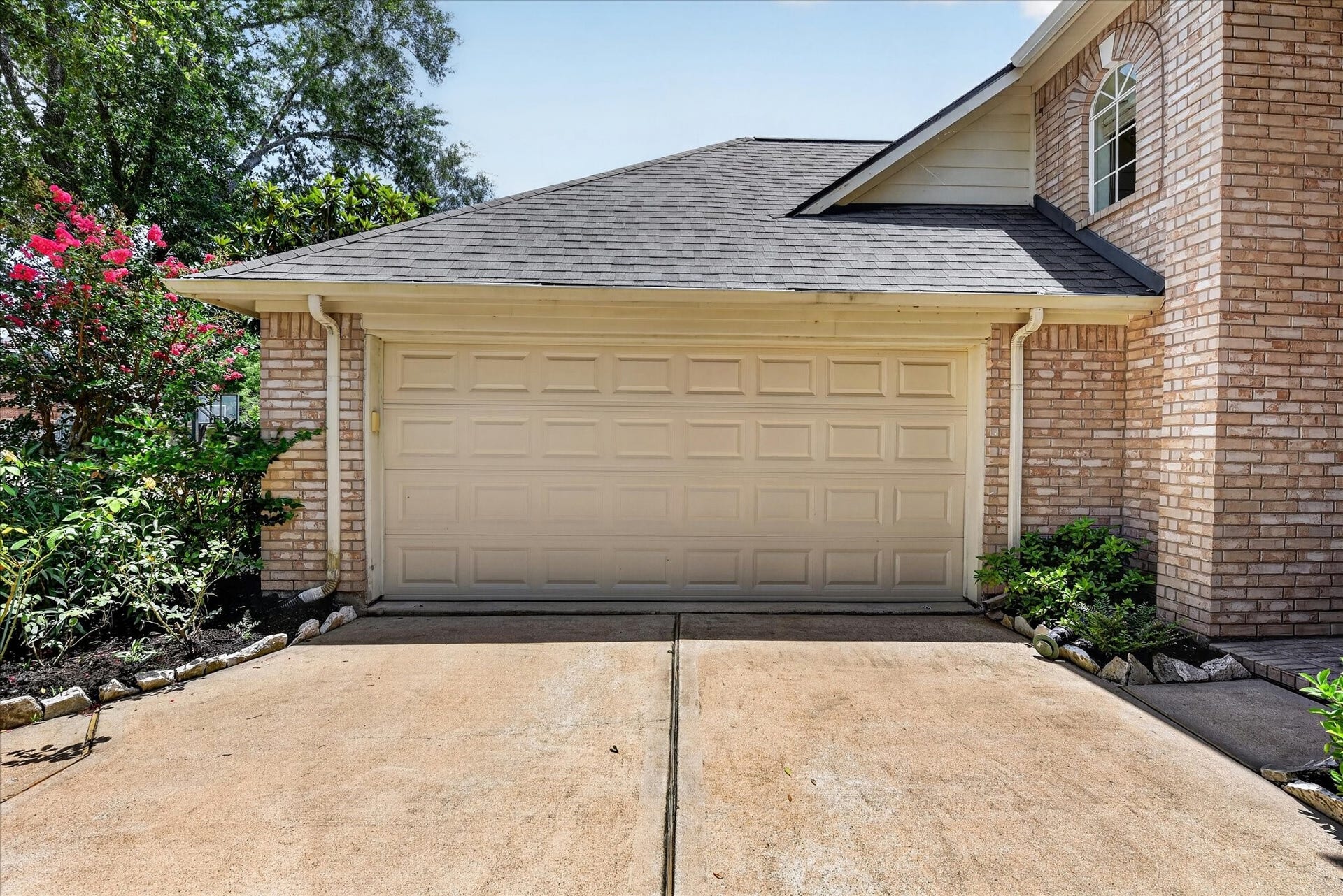 4610 Misty Morning Court, Missouri City, TX 77459 This photo showcases the brick house with a two-car garage and a clean driveway. The exterior is complemented by well-maintained landscaping with shrubs and flowering plants, creating an inviting entrance.