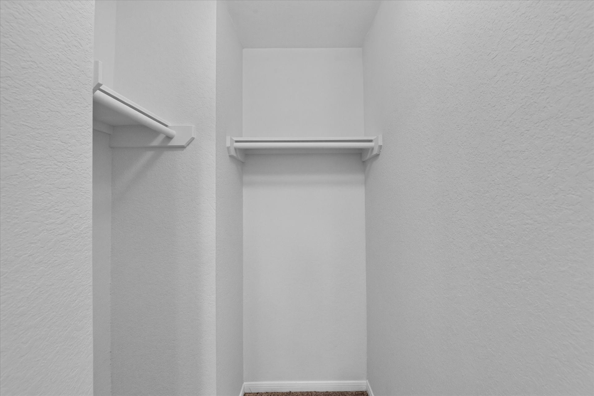 4610 Misty Morning Court, Missouri City, TX 77459 This photo shows a compact, walk-in closet with white walls and shelving, ideal for organizing clothes and accessories.