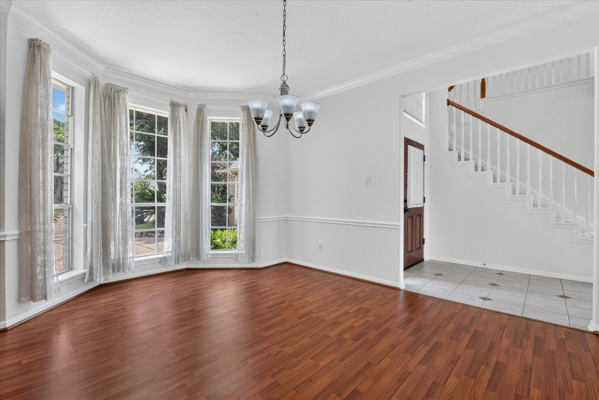 4610 Misty Morning Court, Missouri City, TX 77459 Bright dining area with large bay windows, elegant chandelier, and wood flooring. Adjacent to the entrance and staircase, offering a welcoming and open space.