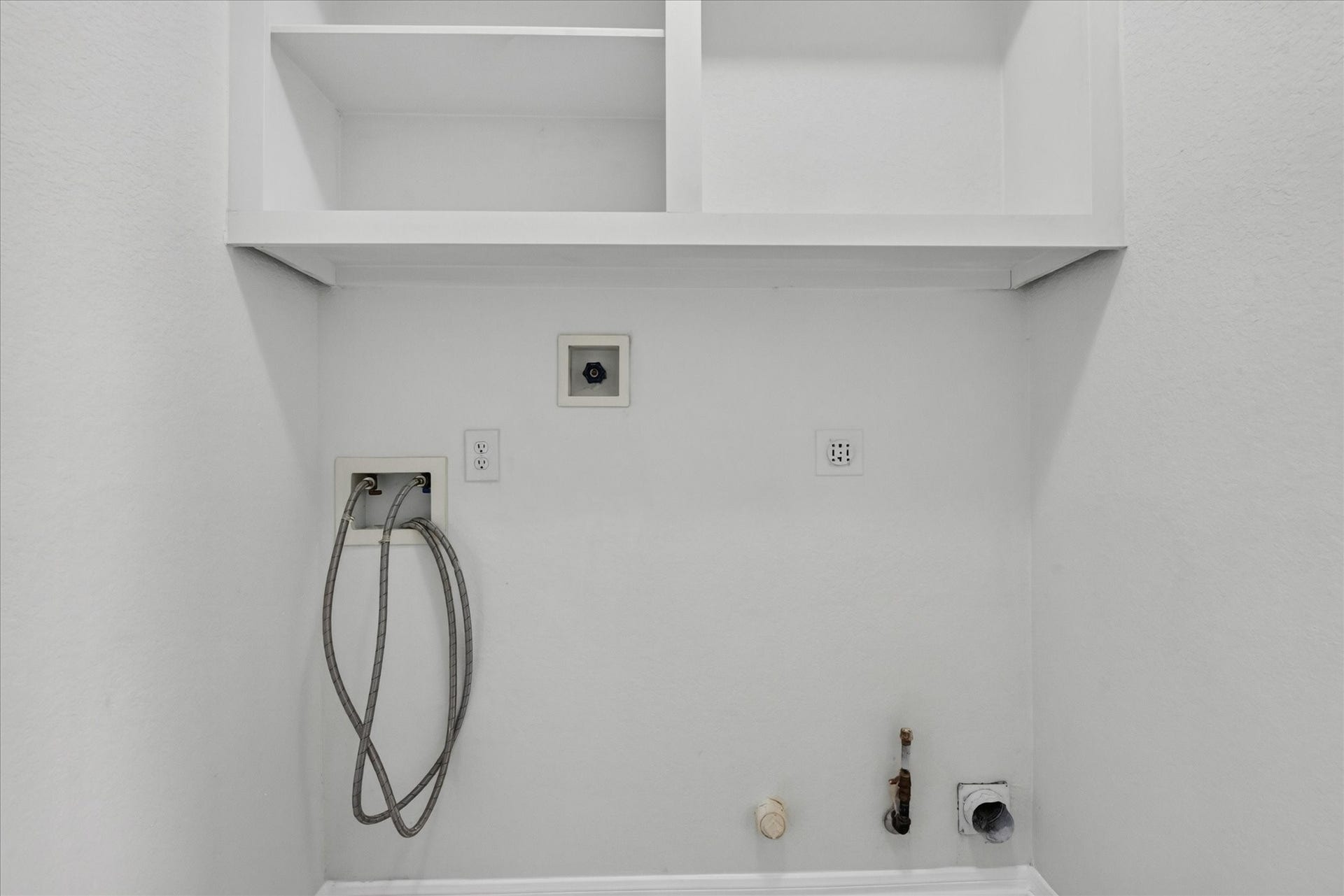 4610 Misty Morning Court, Missouri City, TX 77459 This is a laundry room with hookups for a washer and dryer. It features upper shelving for storage and connections for water, electricity, and ventilation.
