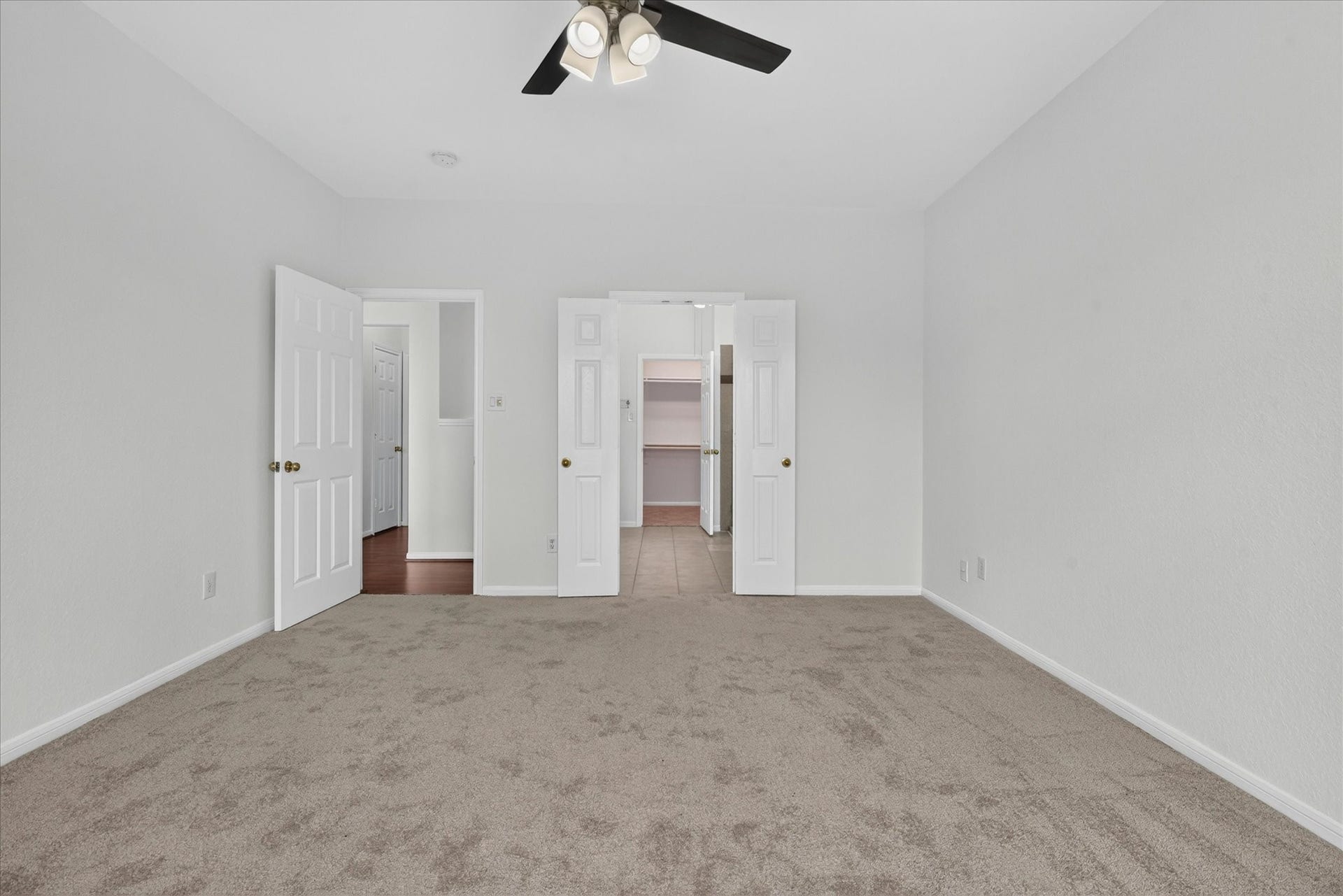 4610 Misty Morning Court, Missouri City, TX 77459 This bedroom features neutral carpet and walls, a ceiling fan, and dual doors leading to a closet. It offers a clean and spacious layout ideal for personalization.