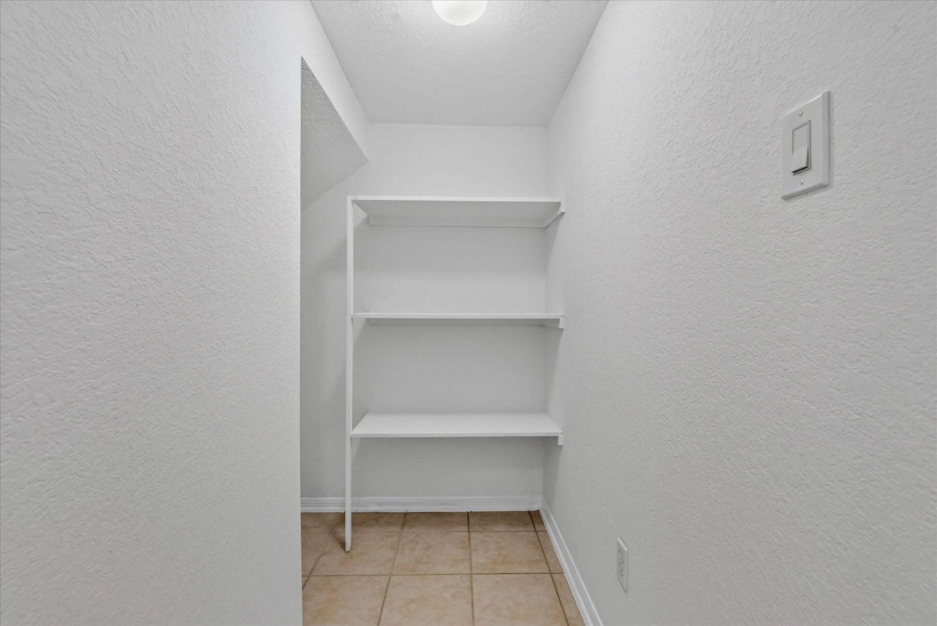 4610 Misty Morning Court, Missouri City, TX 77459 This photo shows a small, well-lit storage space with white walls and three white shelves. The floor is tiled, making it easy to clean.