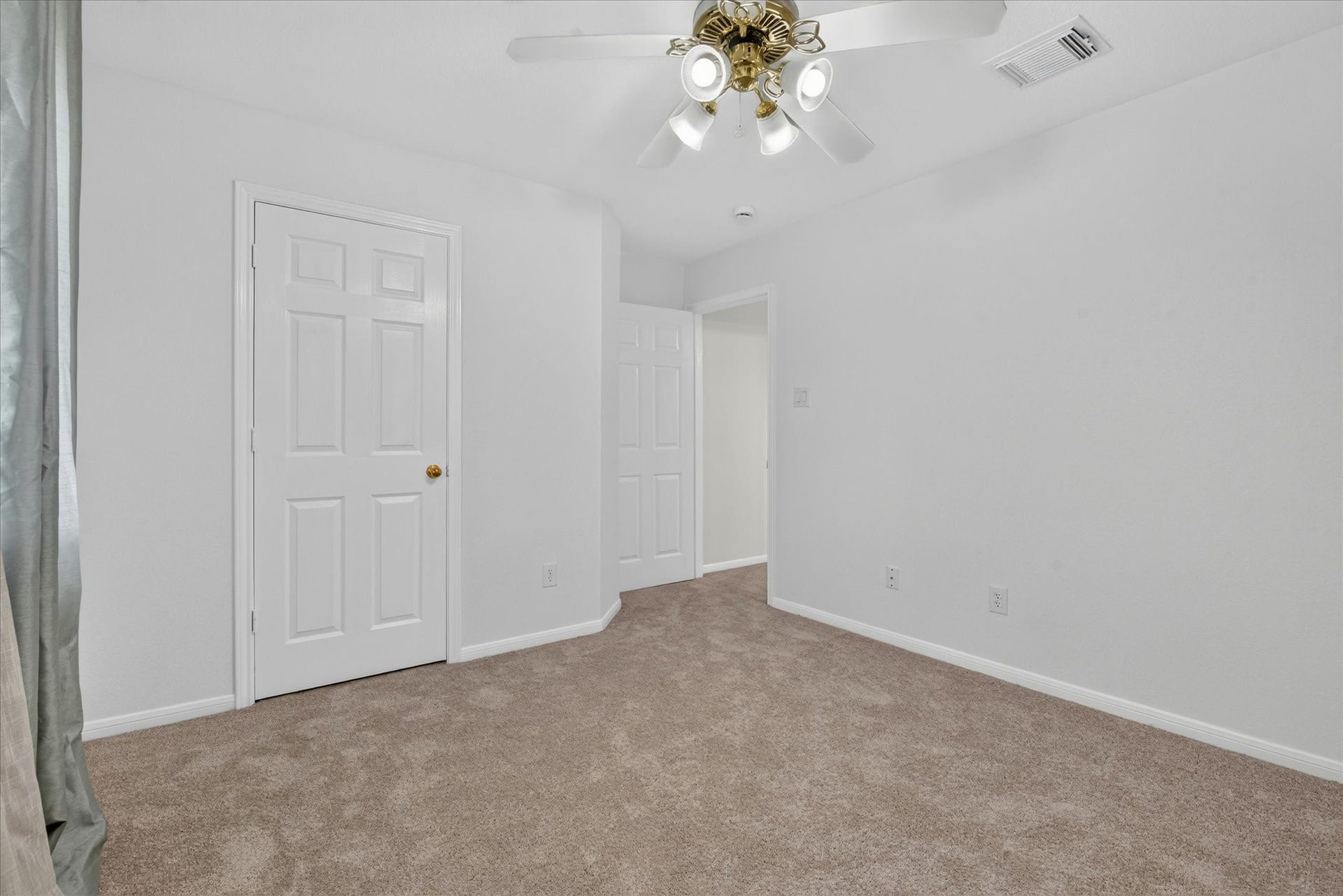 4610 Misty Morning Court, Missouri City, TX 77459 This is another view of a bright, carpeted bedroom with neutral walls, featuring a ceiling fan with lights and two white doors, offering a clean and simple space ready for personalization.