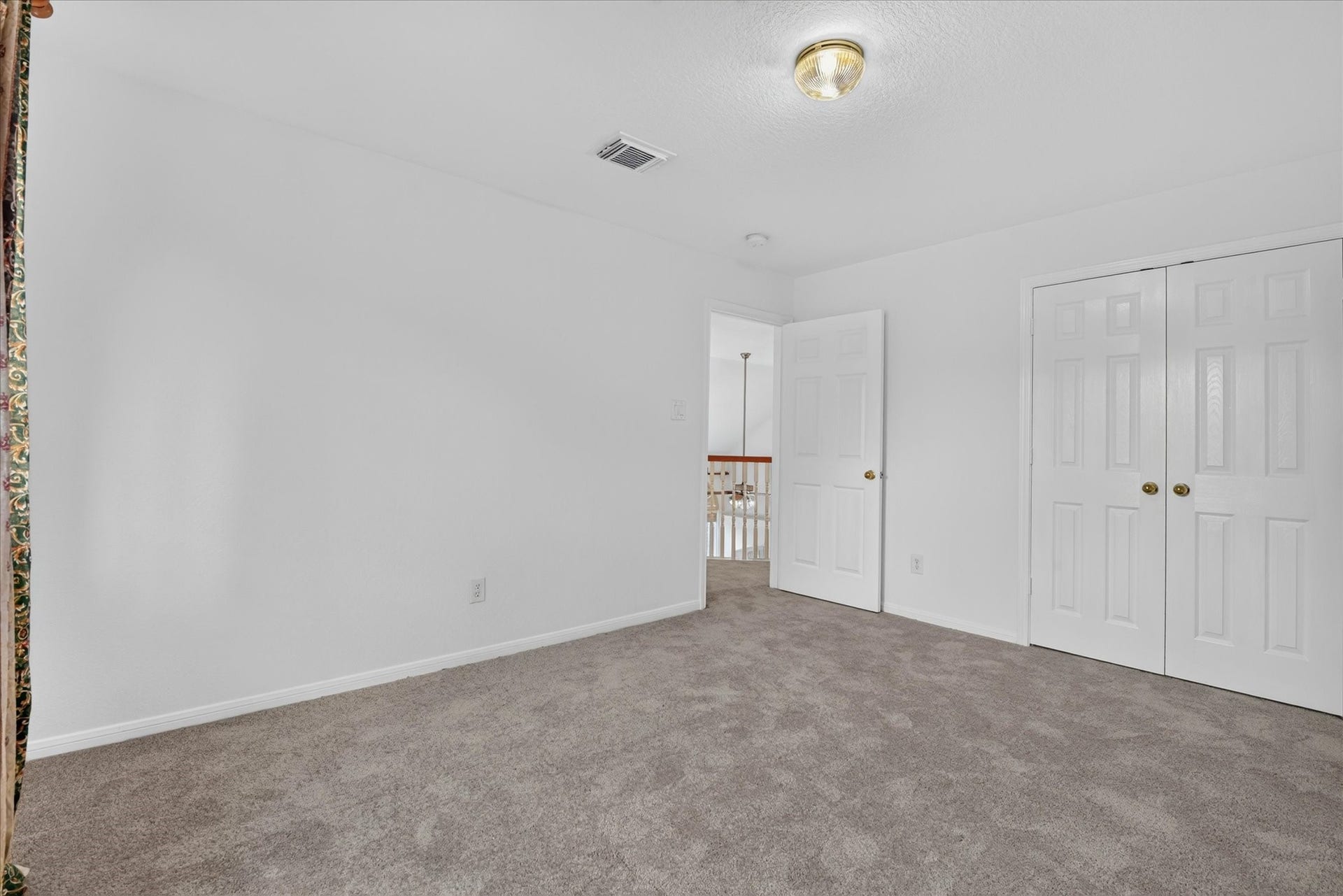 4610 Misty Morning Court, Missouri City, TX 77459 This bedroom features neutral carpet, white walls, a double closet, and a simple light fixture. It connects to a hallway with a view of a stair railing, creating an open feel.