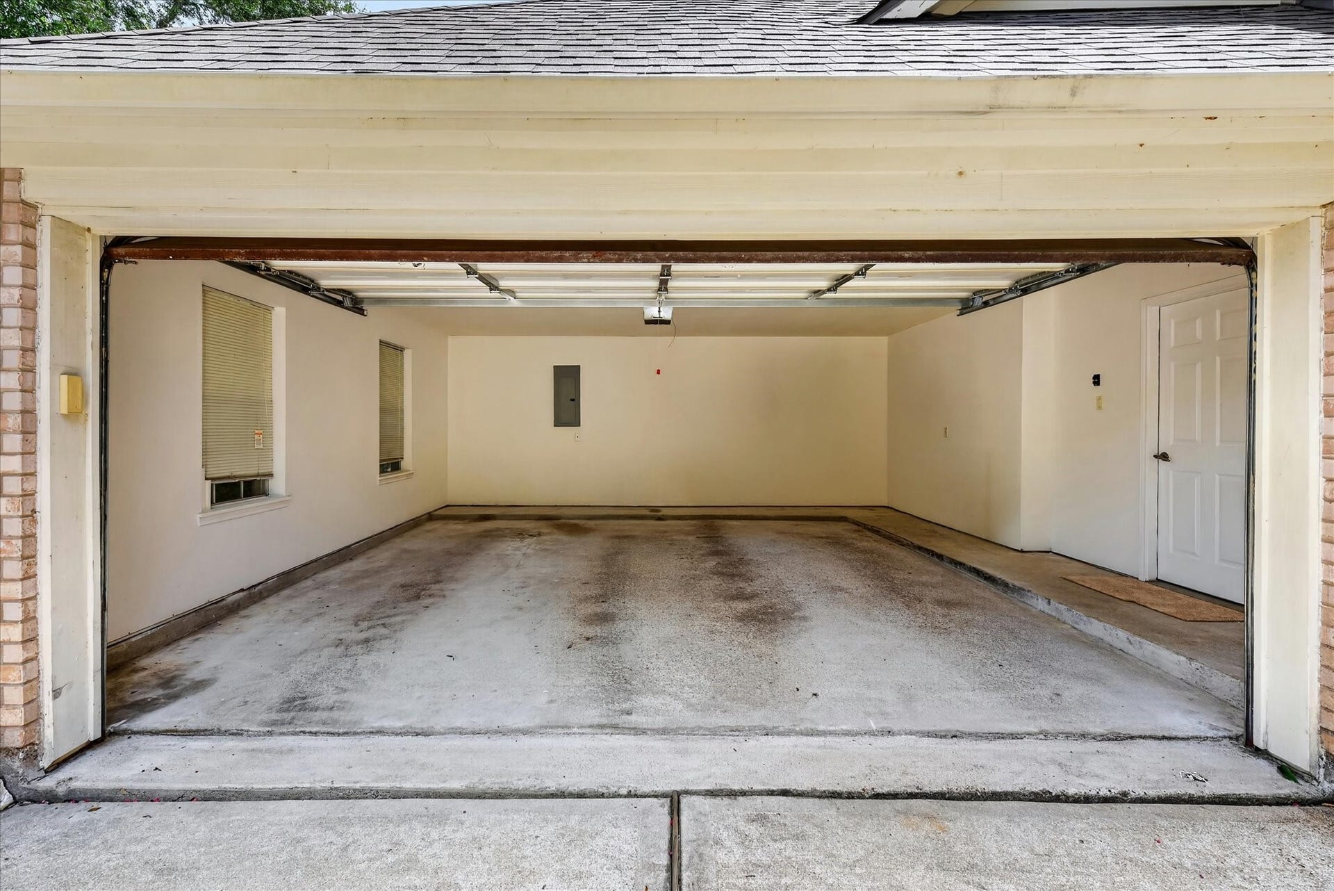 4610 Misty Morning Court, Missouri City, TX 77459 This image shows a spacious two-car garage with clean, neutral-toned walls, two windows for natural light, and a side entry door. Perfect for parking and storage.