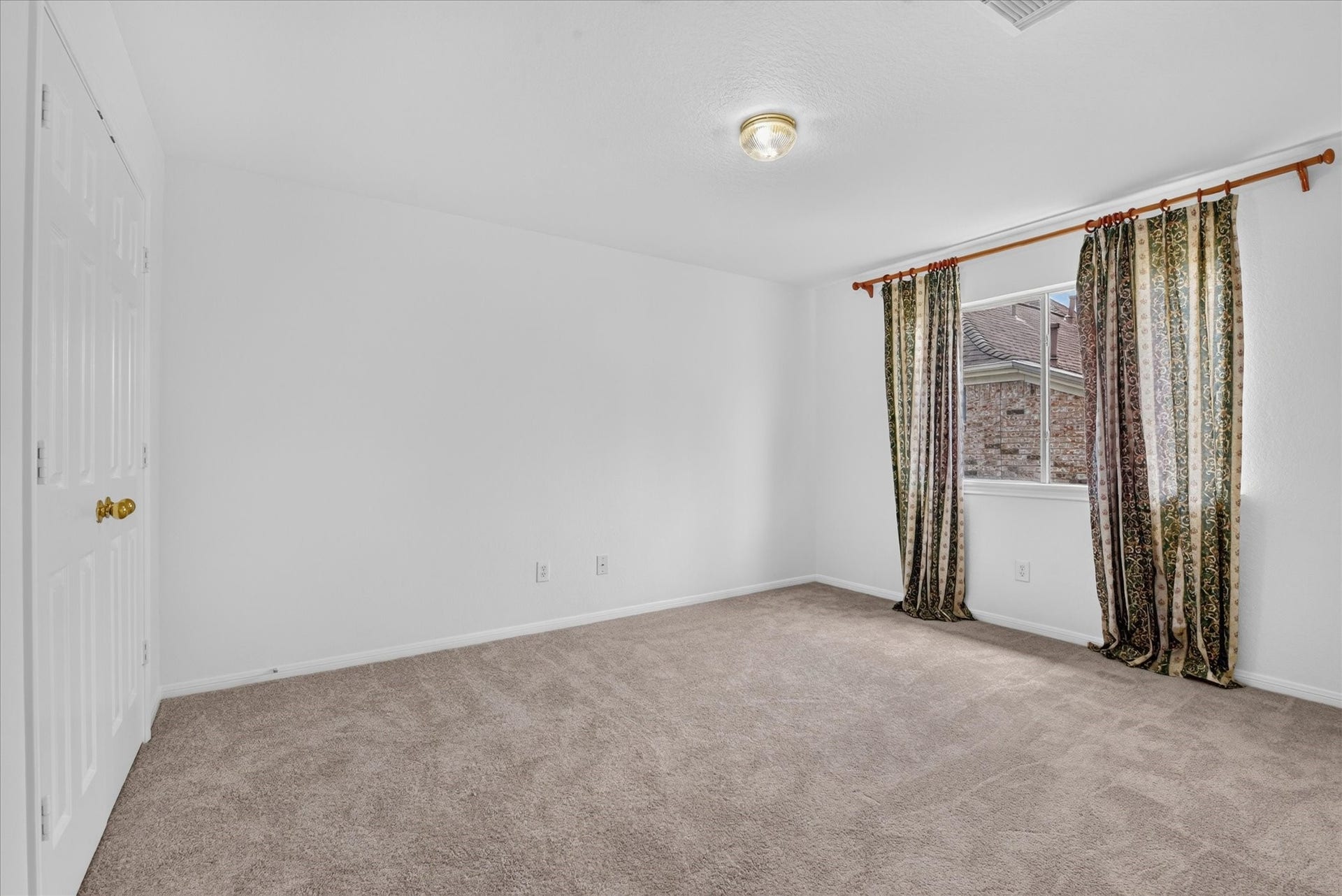 4610 Misty Morning Court, Missouri City, TX 77459 This bedroom view features neutral carpet, white walls, and a ceiling light. It has a window with patterned curtains allowing natural light, and a double door closet for storage.