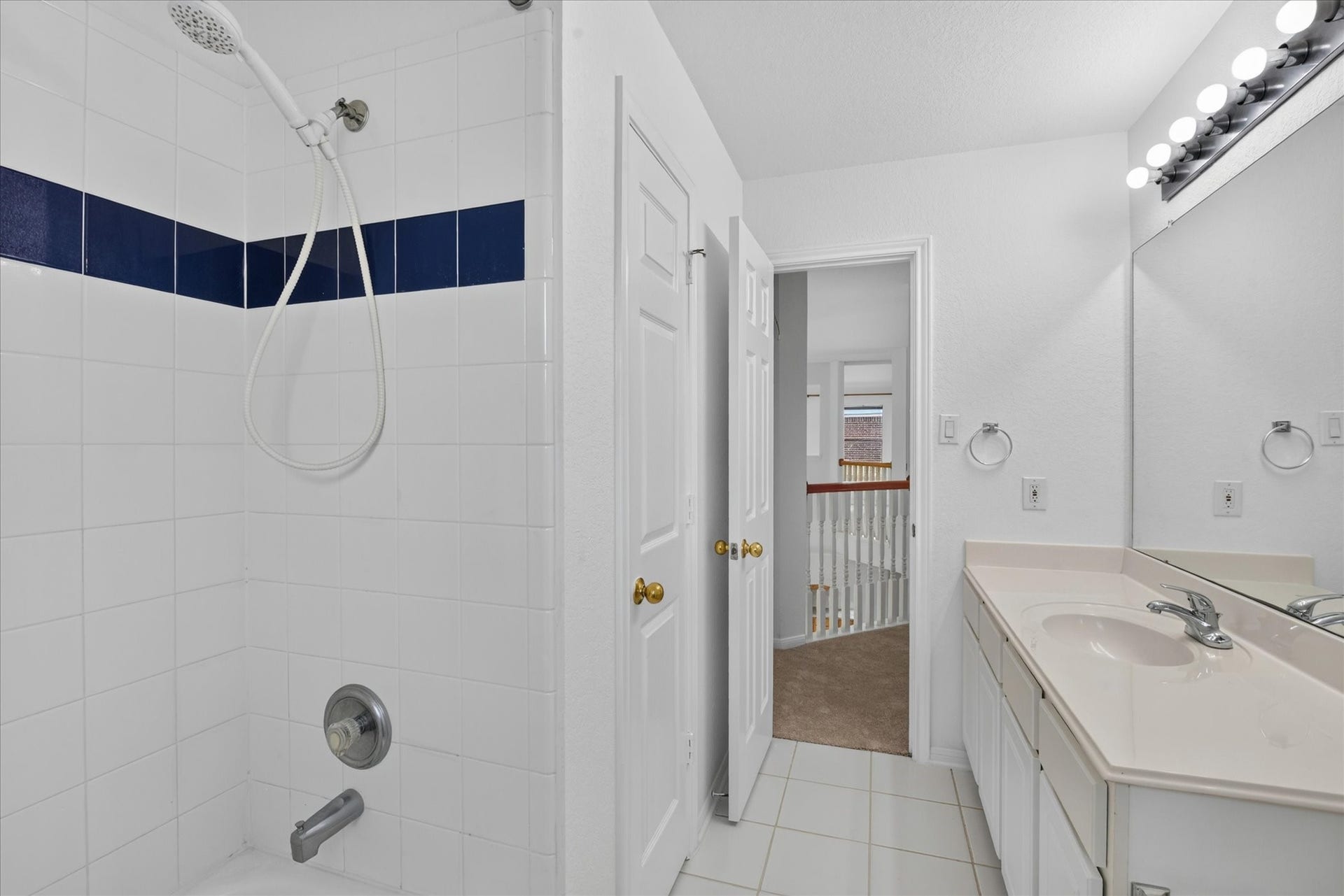 4610 Misty Morning Court, Missouri City, TX 77459 Another view of the full bathroom features a clean, modern design with white tile and a contrasting blue accent in the shower. It includes a spacious vanity with a large mirror and bright lighting, creating a fresh and inviting atmosphere.