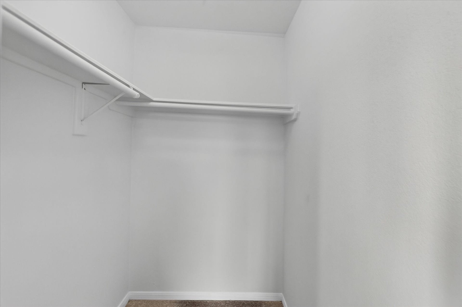 4610 Misty Morning Court, Missouri City, TX 77459 This photo shows a spacious walk-in closet near the Gameroom with white walls, a high ceiling, and a single hanging rod for clothing storage.