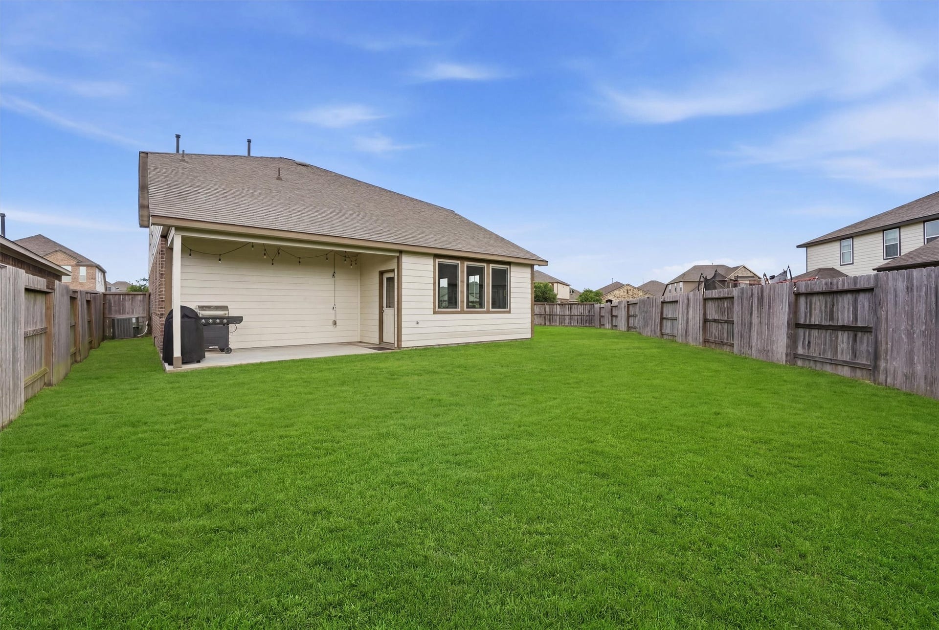 2130 Shellbark Way, La Marque, TX 77568 Spacious backyard with well-maintained lawn, a covered patio area, and wooden fencing, perfect for outdoor activities and entertaining.