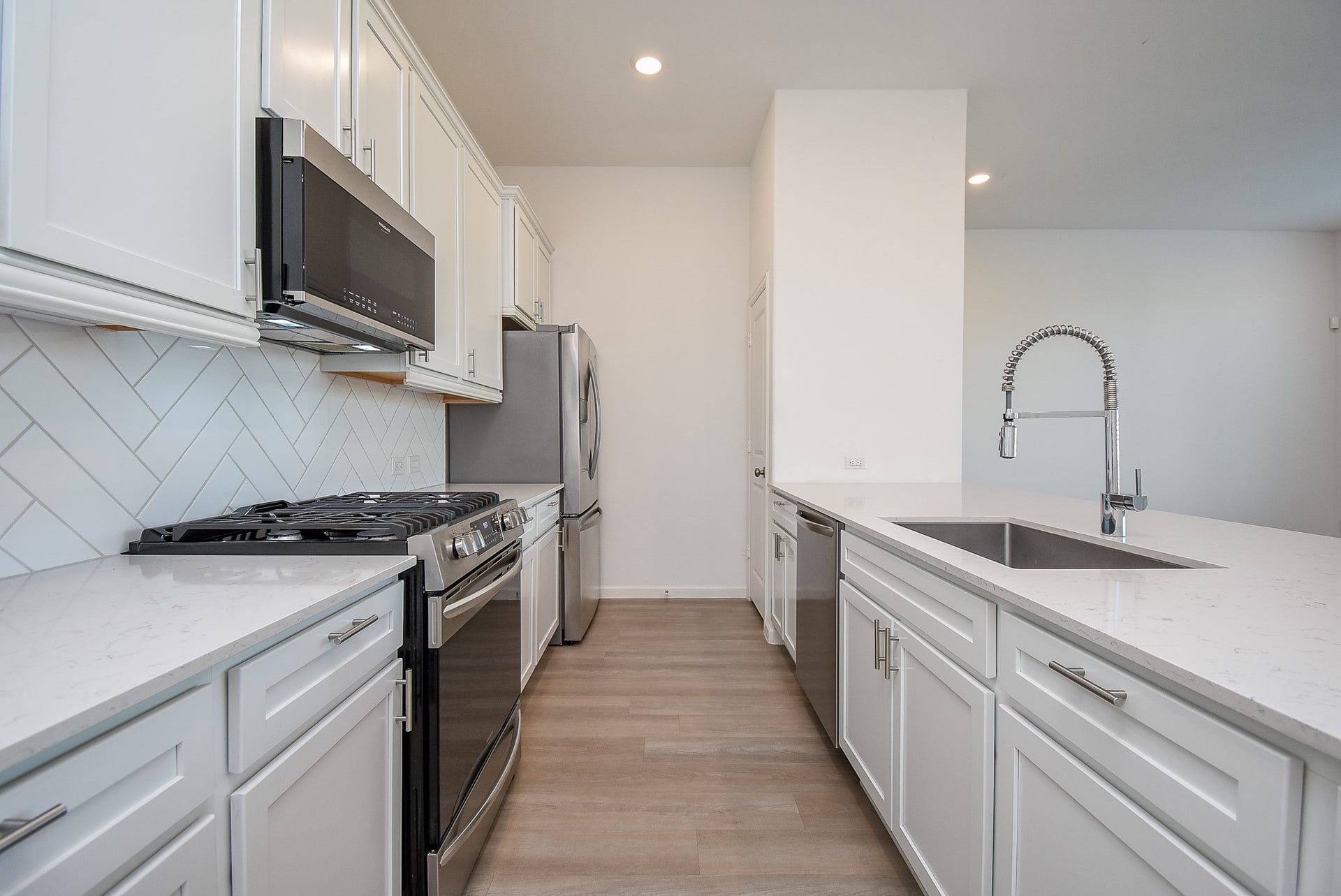 The kitchen is equipped with a stainless steel gas stove, built-in microwave, and refrigerator, offering a sleek and functional cooking space. The pantry is located at the back, providing ample storage.