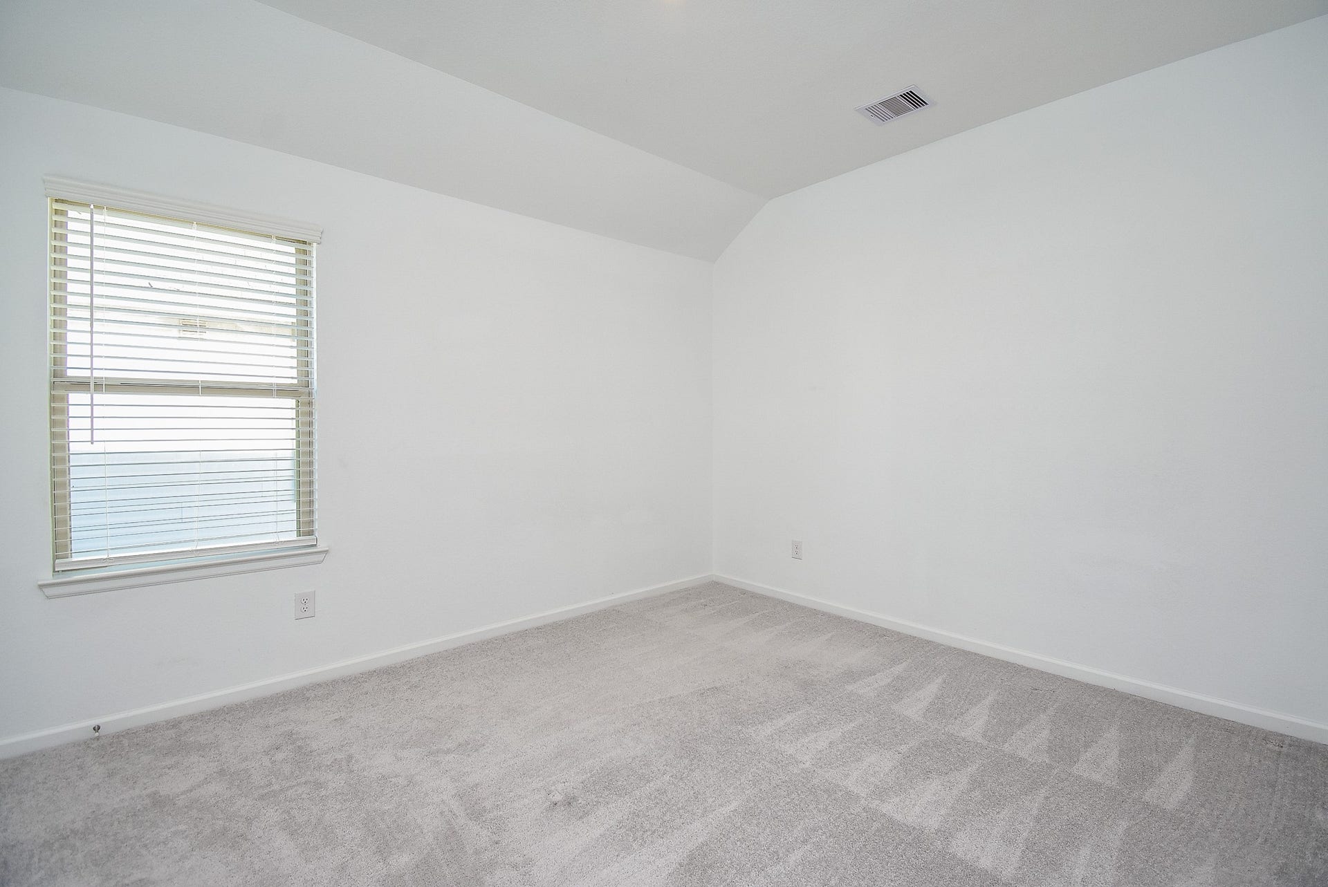 One of the two secondary bedrooms with neutral carpeting and large window.