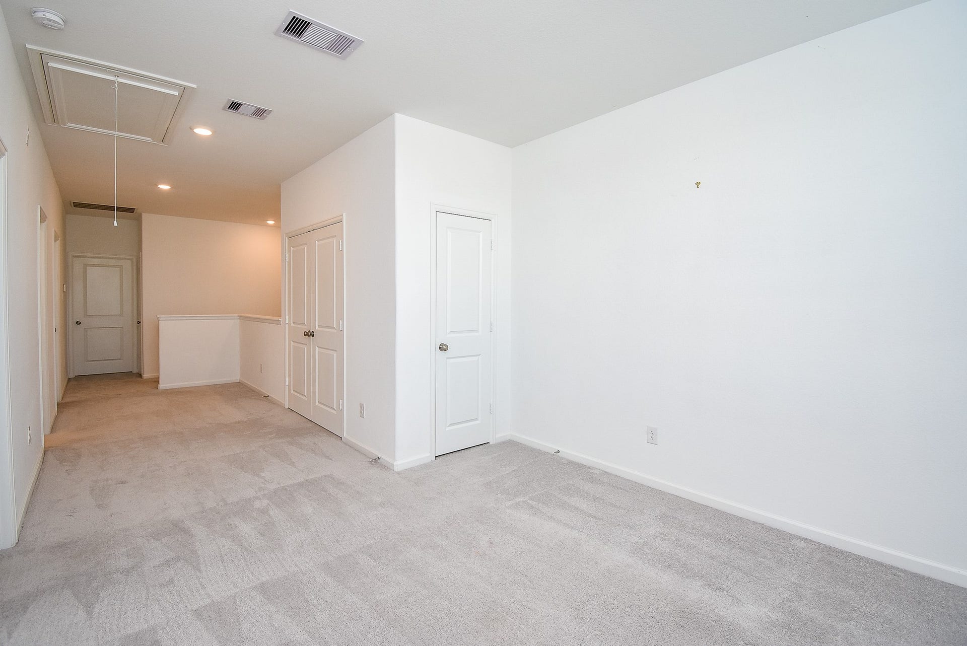 A reversed view from the flex room showing the attic storage, storage closet and utility closet behind the double doors.
