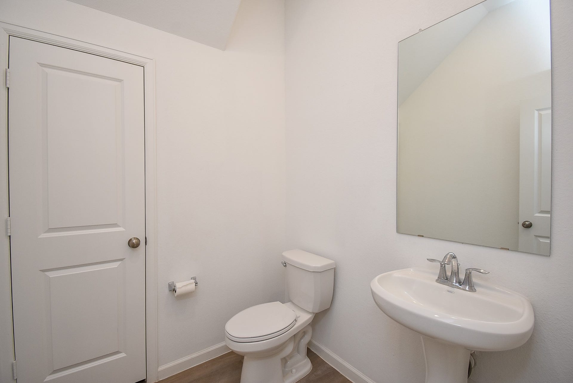 First floor half bath featuring a pedestal sink, easily accessible from the main living area or the garage.  Just beyond that door is a large storage closet