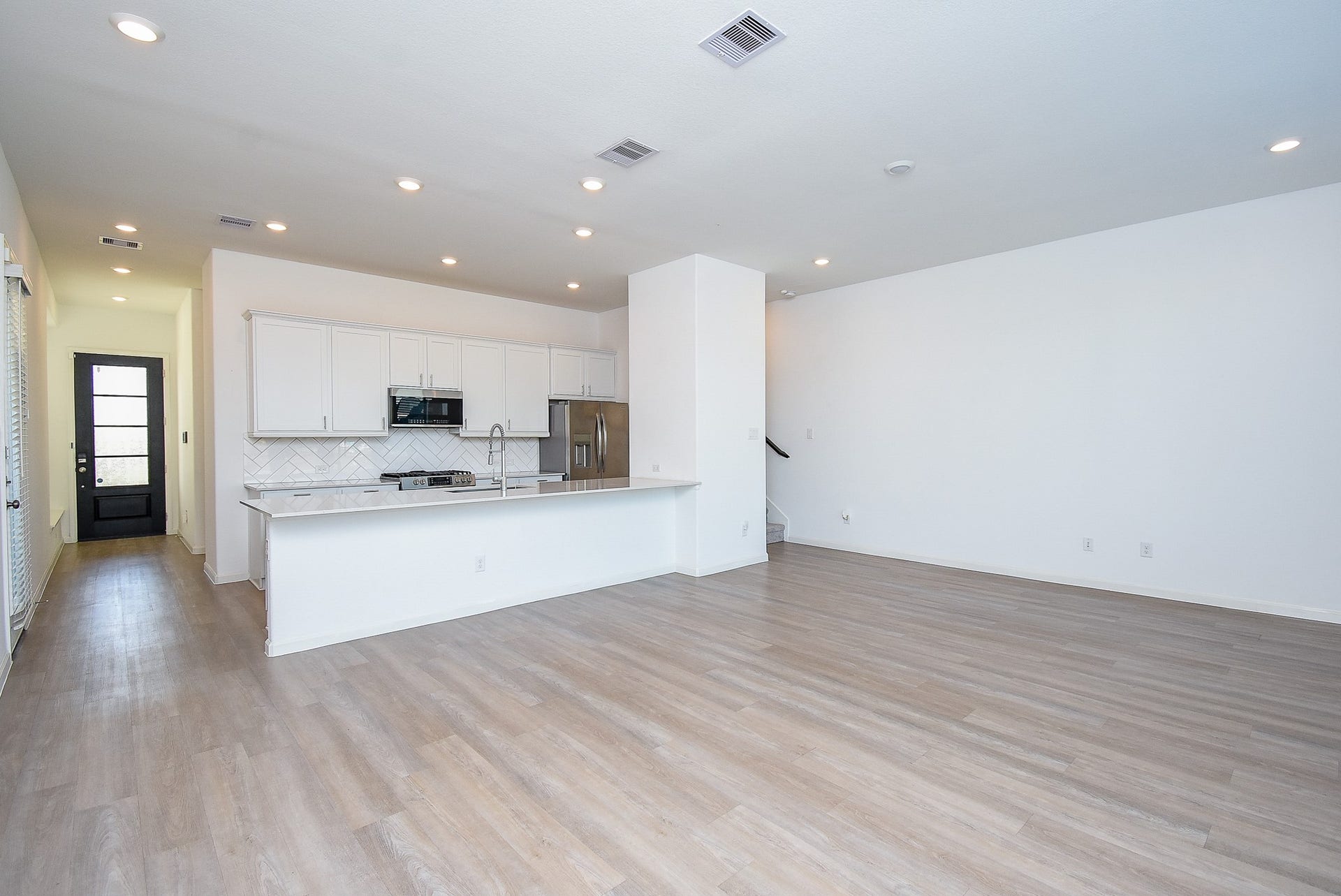 The kitchen island with a bar for stools, seamlessly flows into the dining space and family room, creating an inviting and functional living space with modern finishes and recessed lighting.