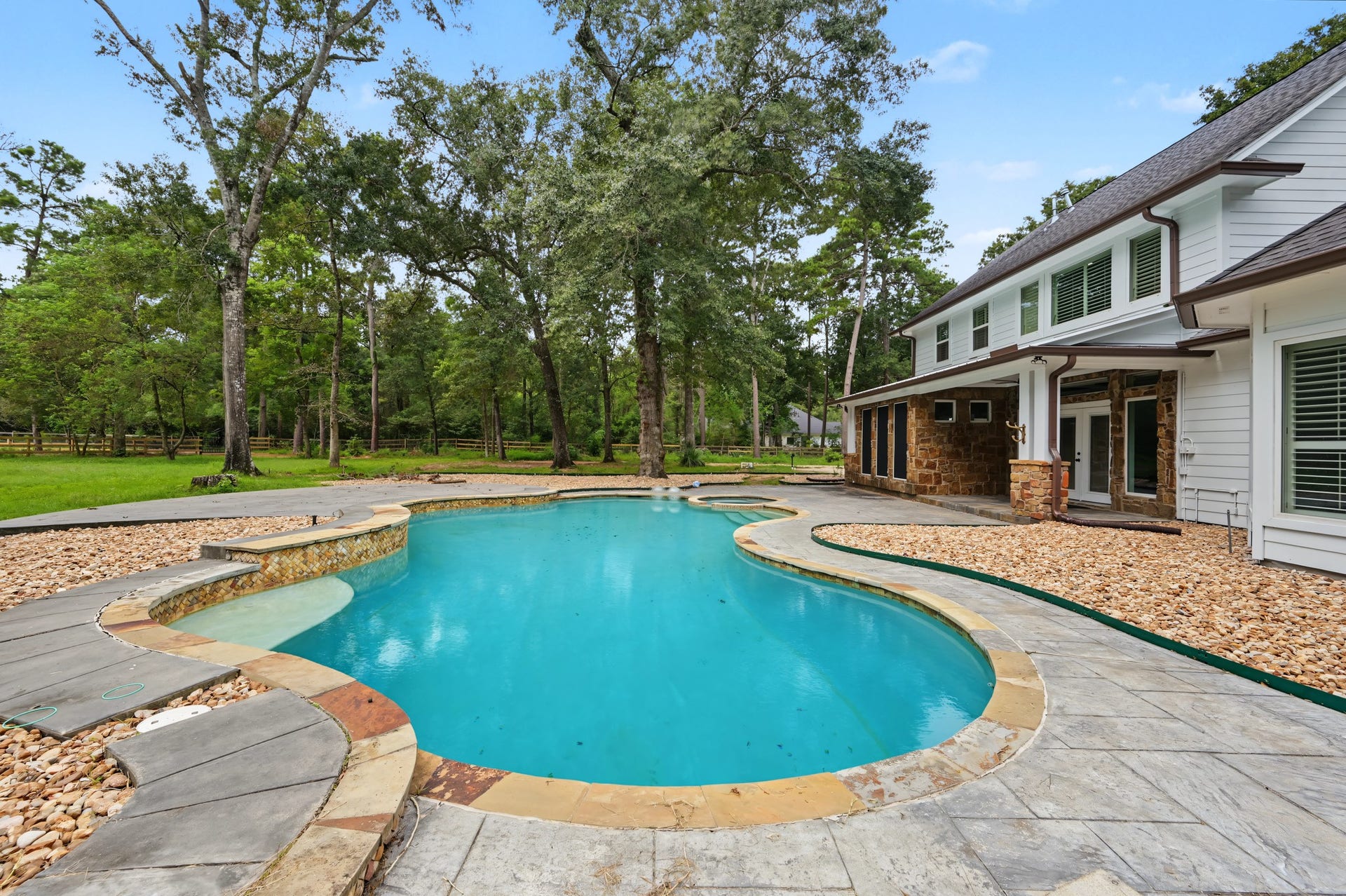 Experience luxury with this stunning backyard oasis featuring an inviting pool surrounded by lush greenery and elegant stonework, perfect for relaxation and entertaining.