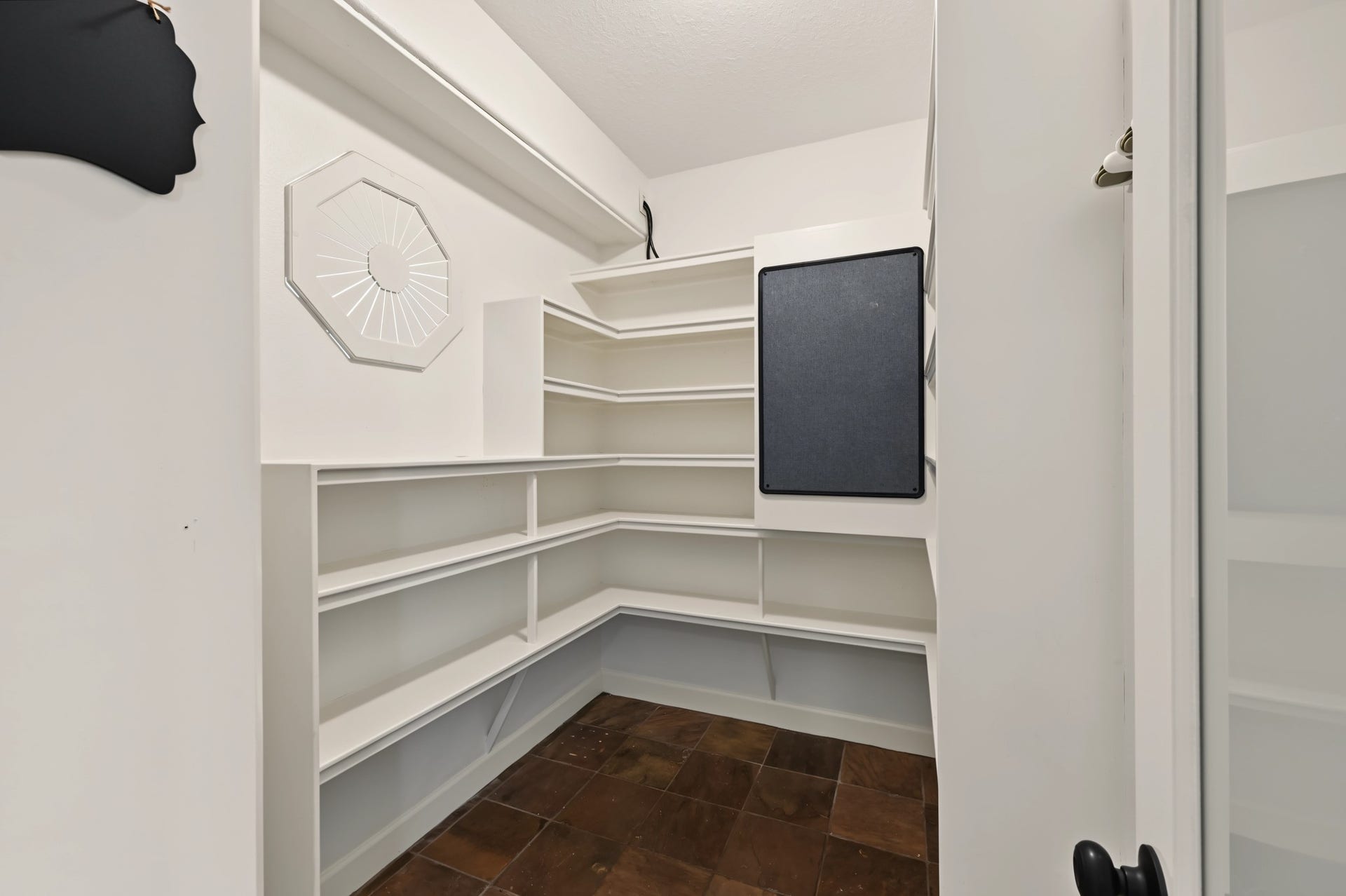 Spacious pantry with ample shelving and tile flooring, ideal for organized storage.
