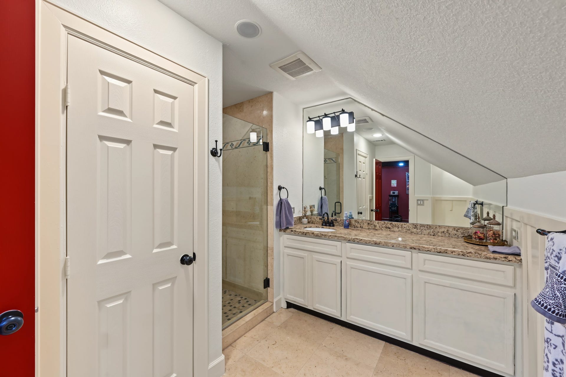 Spacious full bathroom just off the movie room with elegant granite countertop, complete with a glass-enclosed shower and recessed lighting.