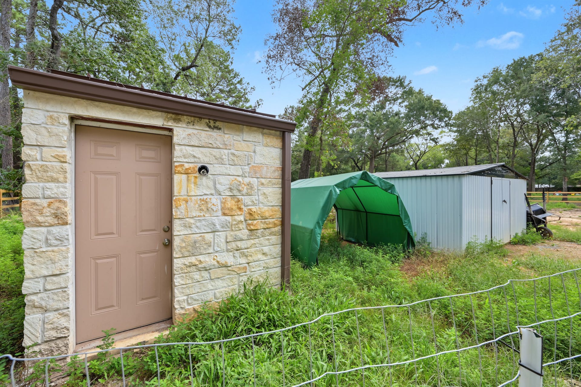 Brand new private well house, accompanied by a versatile metal storage/tool shed and a convenient green canopy, perfect for outdoor storage or activities.